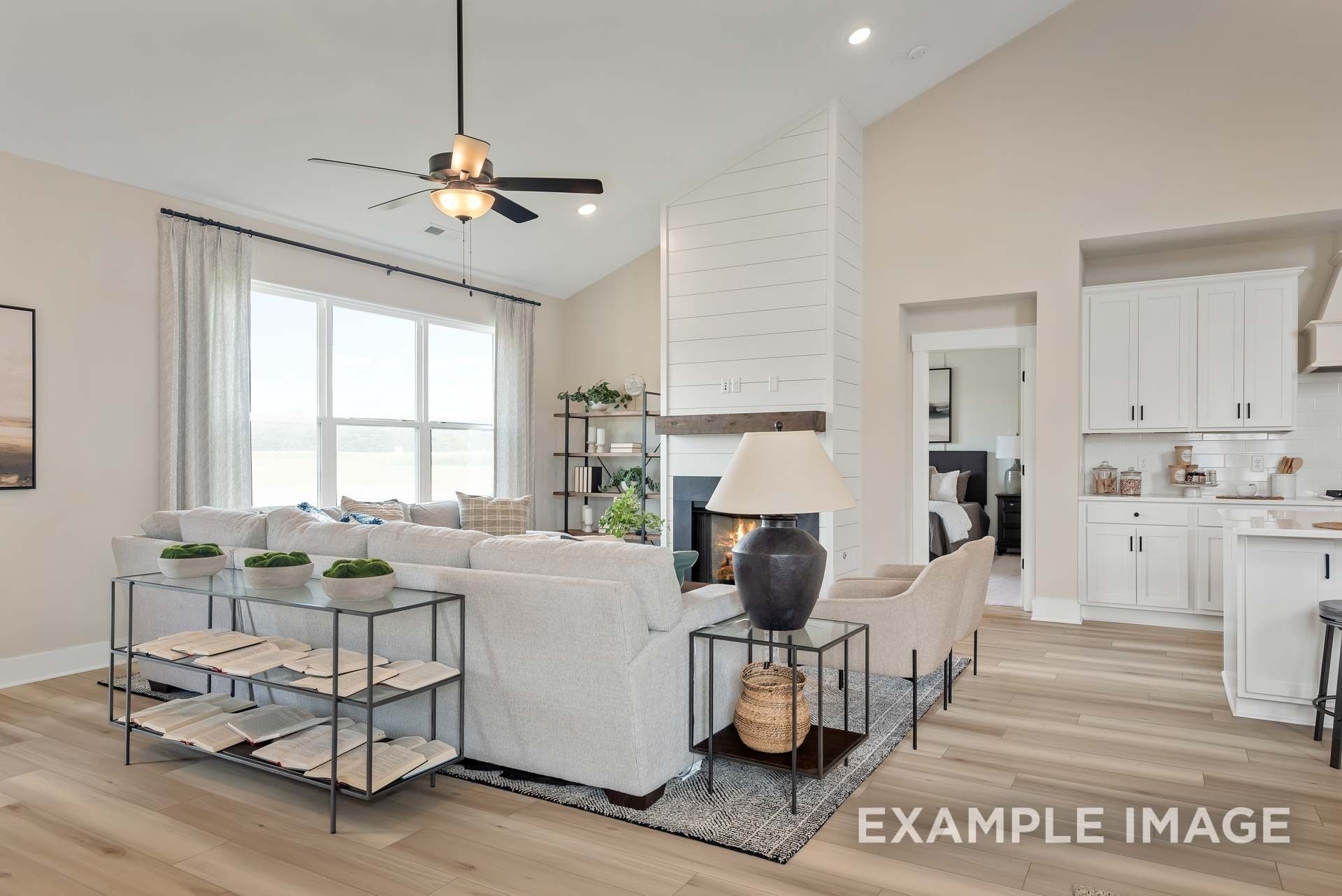 Cozy living room with white shiplap fireplace, beige sofa, large windows, open to kitchen in Davidson Homes Ridgeport C, Gallatin TN