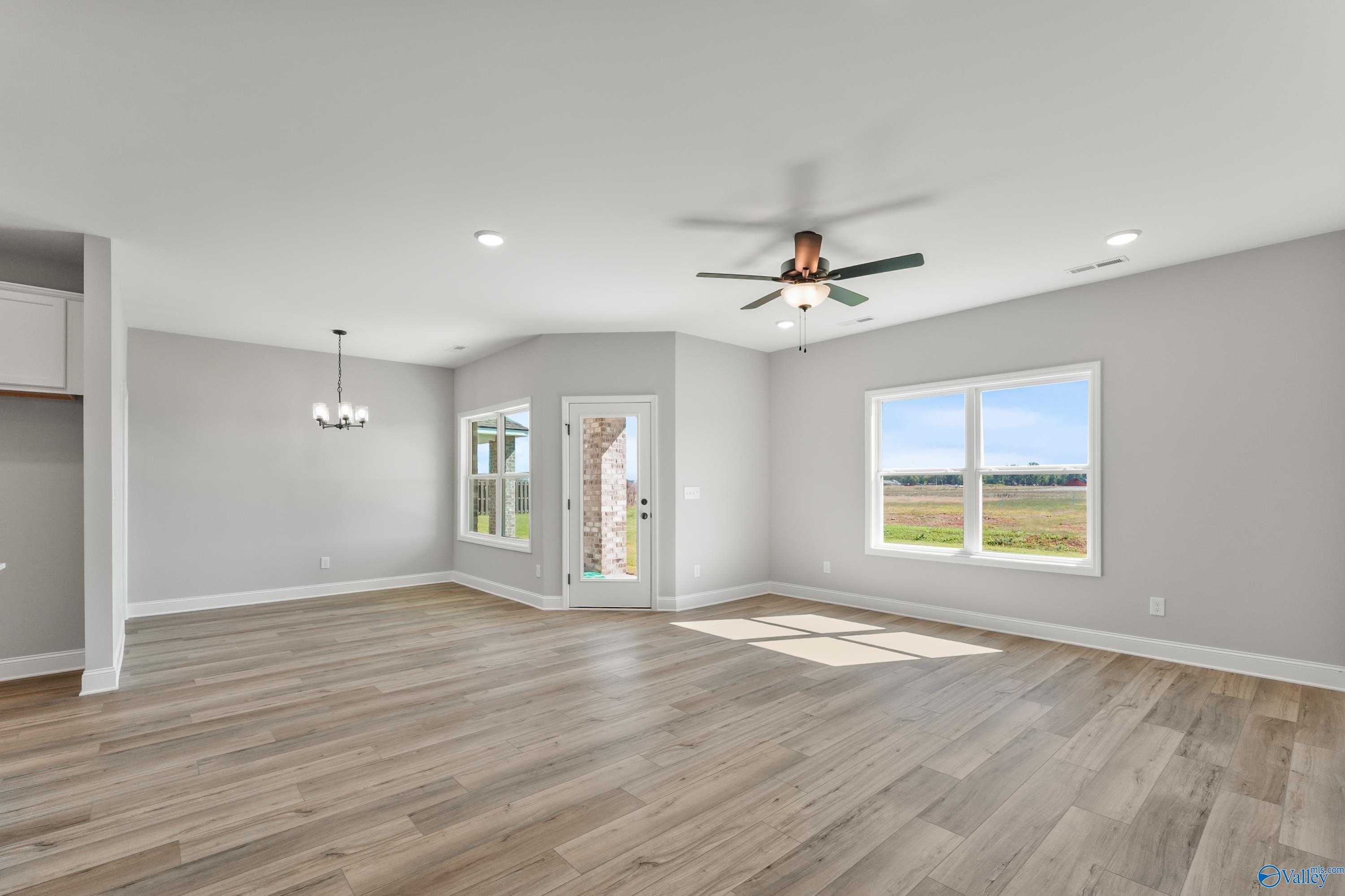 Bright open living room with hardwood floors, large windows to fields, ceiling fan in The Daphne C, Davidson Homes, Hazel Green, AL