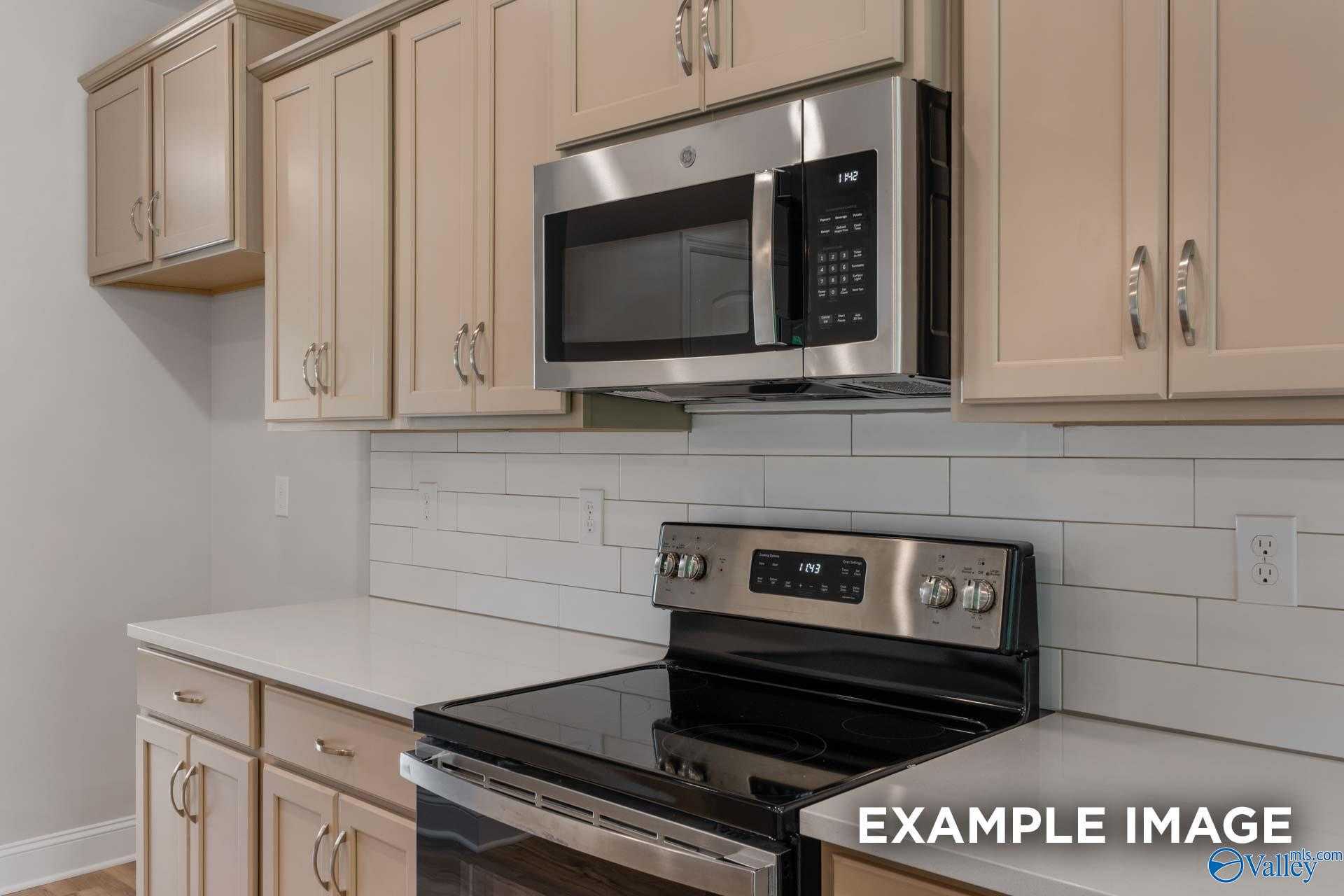 Modern kitchen featuring stainless steel microwave and range, beige cabinets, subway tile backsplash in The Shelby C by Davidson Homes, Meridianville, AL