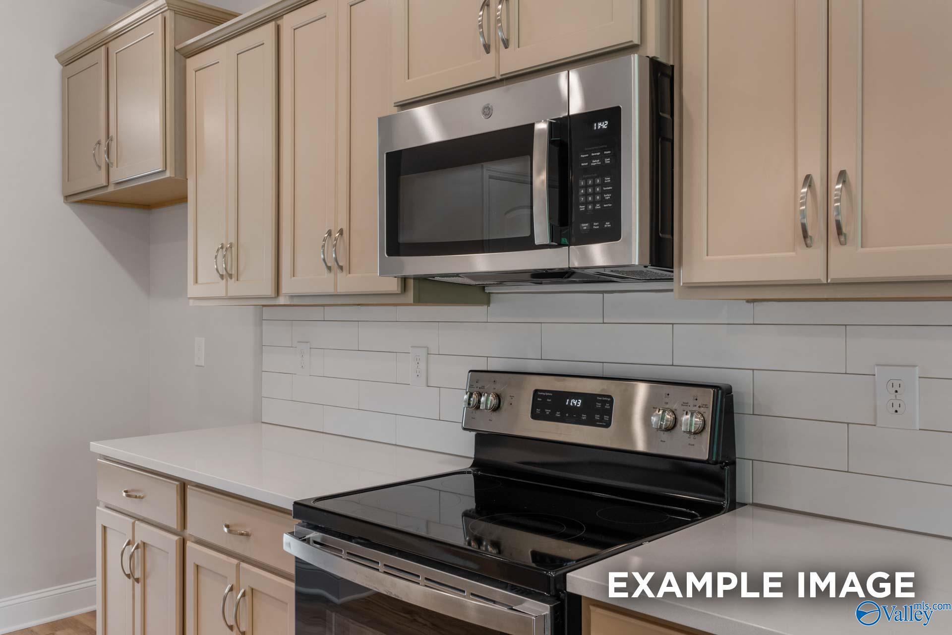 Modern kitchen featuring stainless steel microwave and range, beige cabinets, subway tile backsplash in The Shelby C by Davidson Homes, Meridianville, AL