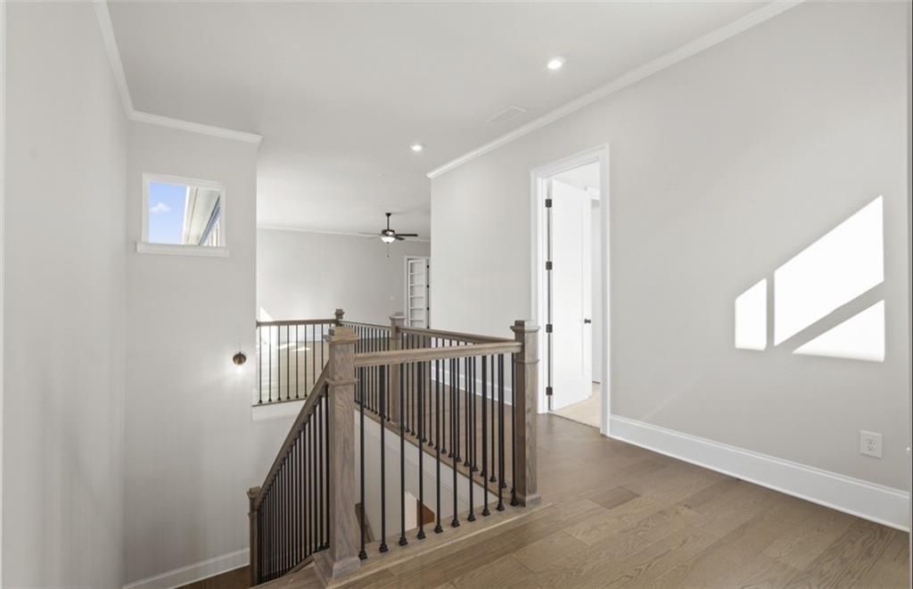 Grand wooden staircase with iron balusters, hardwood floors, and natural light in two-story The Seaside A home by Davidson Homes, Woodstock, GA