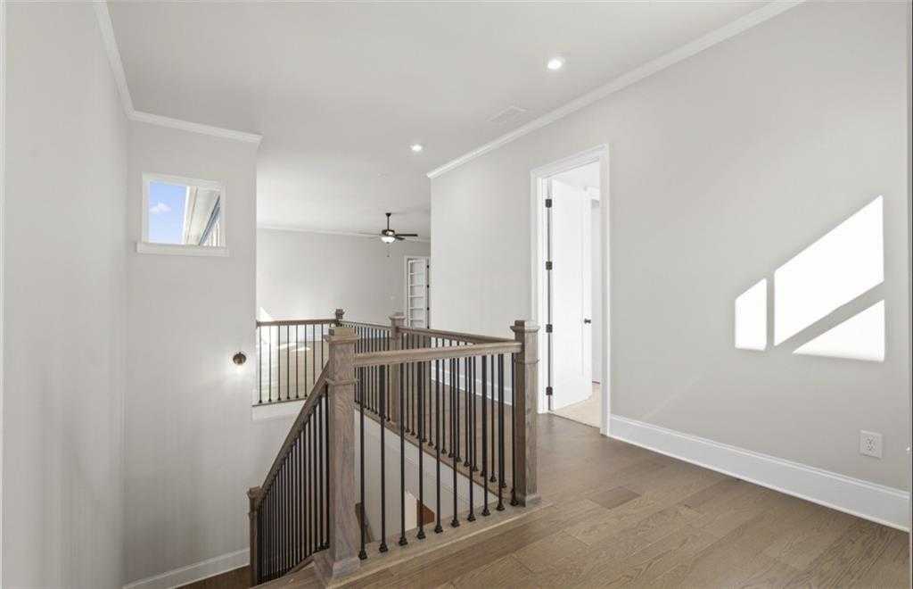 Grand wooden staircase with iron balusters, hardwood floors, and natural light in two-story The Seaside A home by Davidson Homes, Woodstock, GA