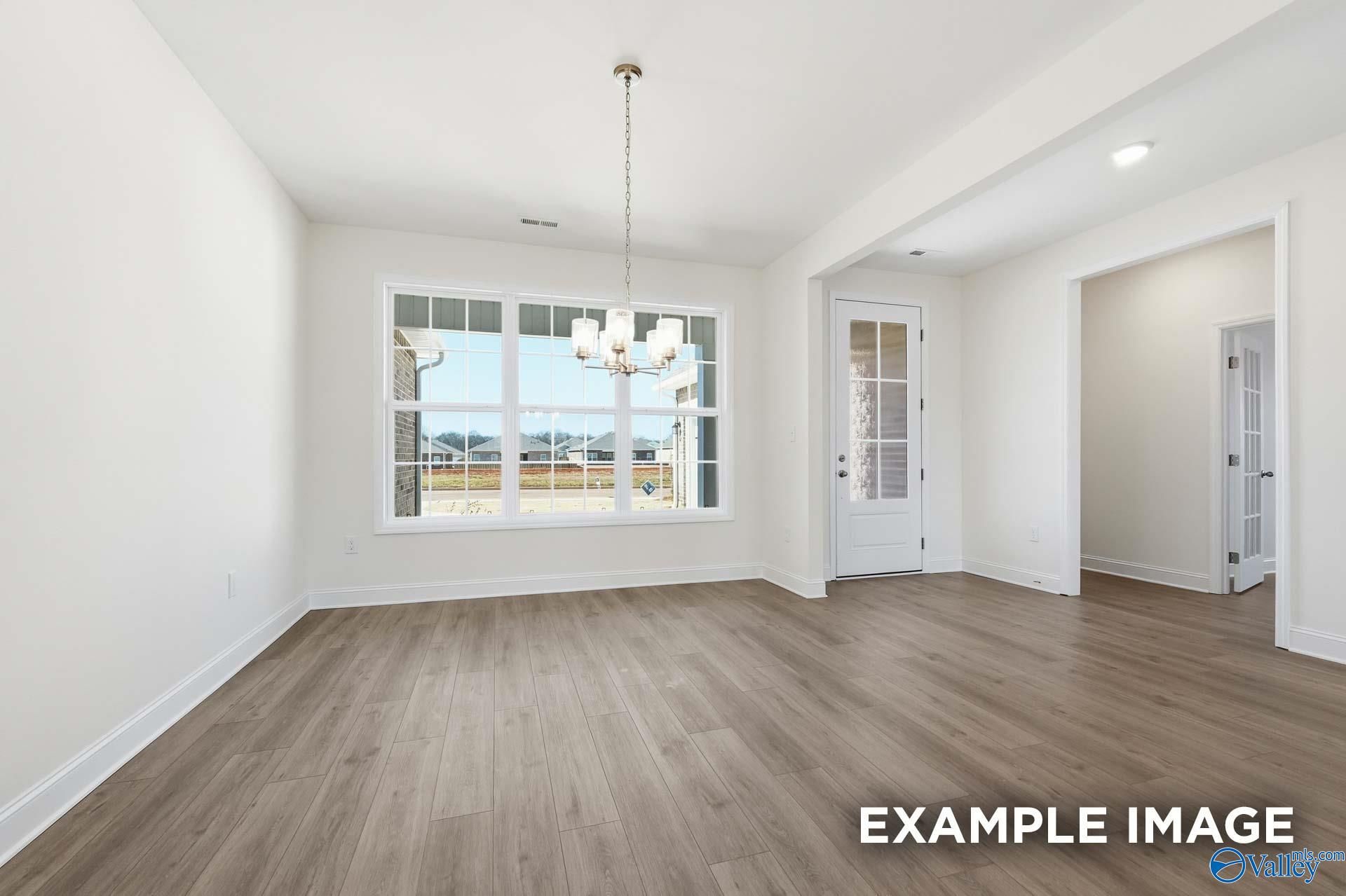 Bright dining area with wood-look flooring and chandelier in The Valencia floor plan at Briercreek in Meridianville, AL.
