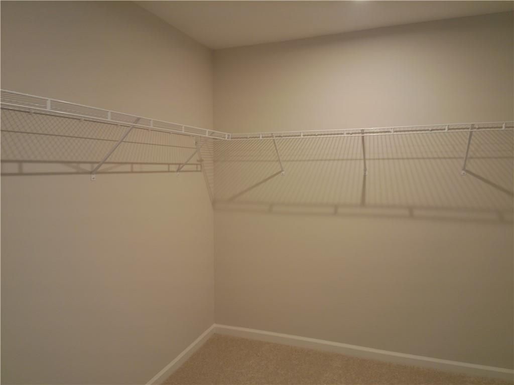 Spacious walk-in closet with white wire shelving on beige walls in The Marion C master suite, Davidson Homes, Winder, Georgia