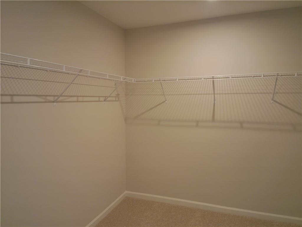 Spacious walk-in closet with white wire shelving on beige walls in The Marion C master suite, Davidson Homes, Winder, Georgia