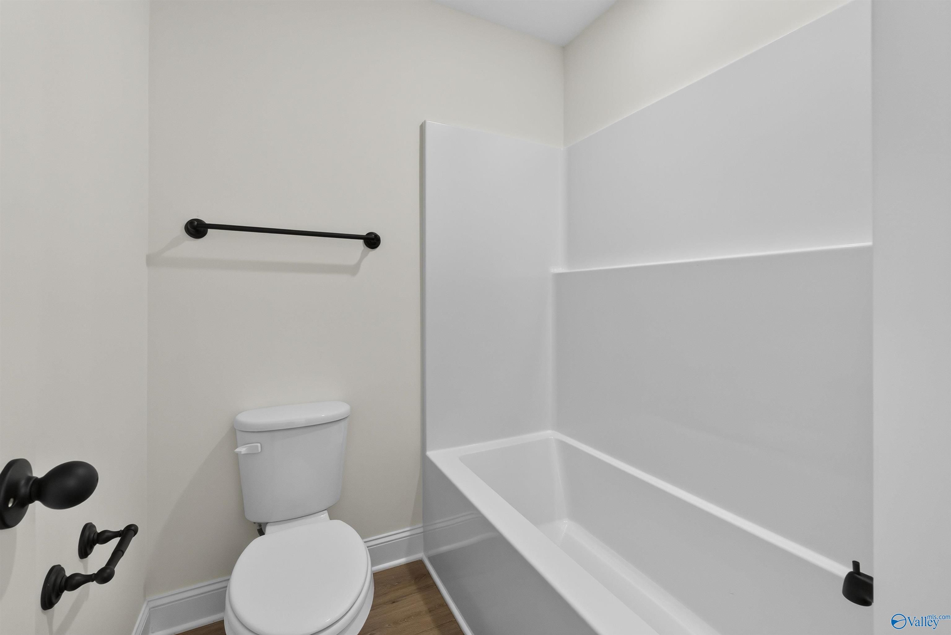Modern bathroom with white tub, toilet, and matte black fixtures in Davidson Homes Ashport L plan, Berry Cove, New Market, AL