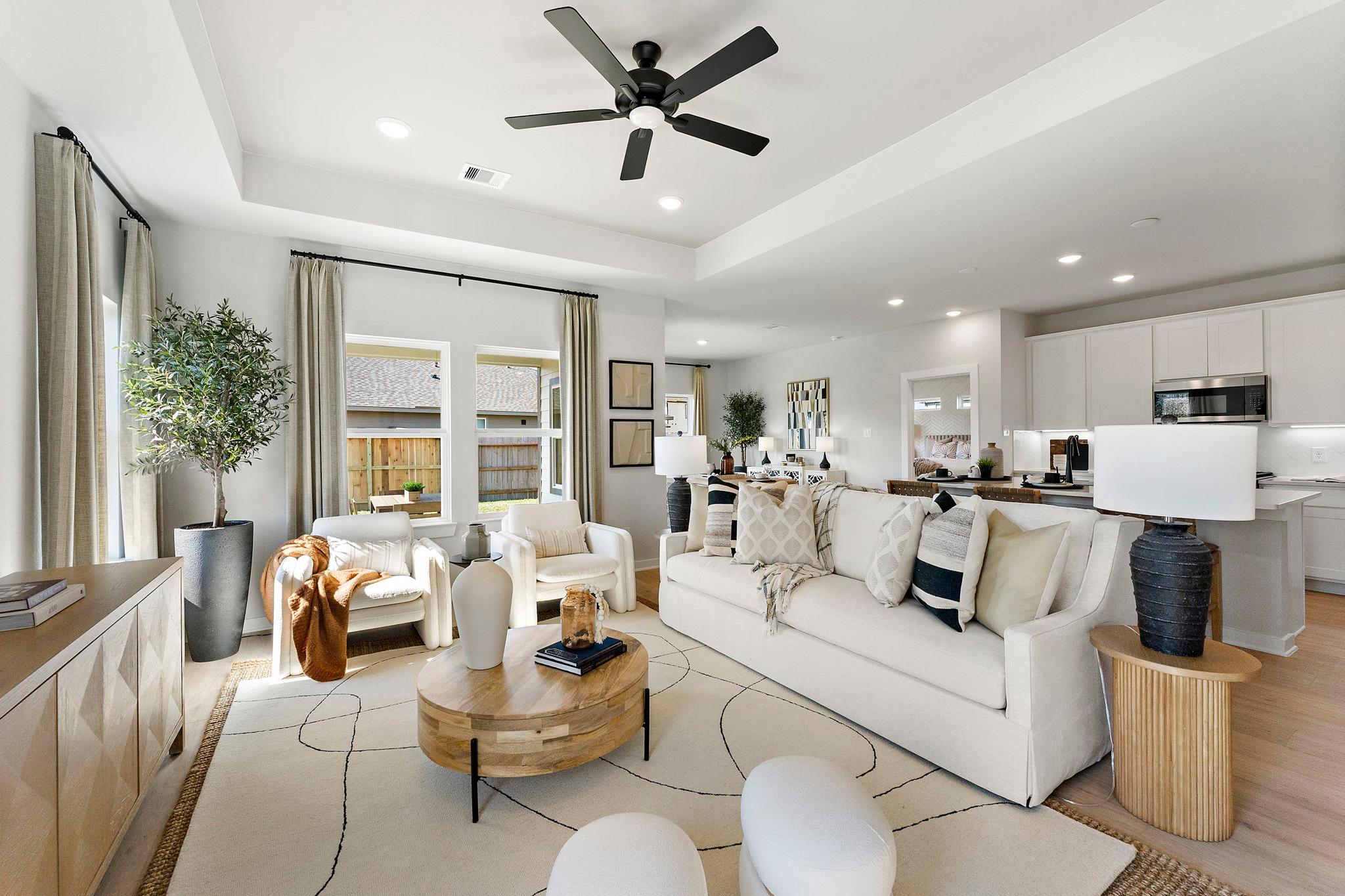 Spacious open-concept living room at Sundance Cove in Crosby Texas by Davidson Homes featuring white sofa wooden coffee table plants and adjacent kitchen