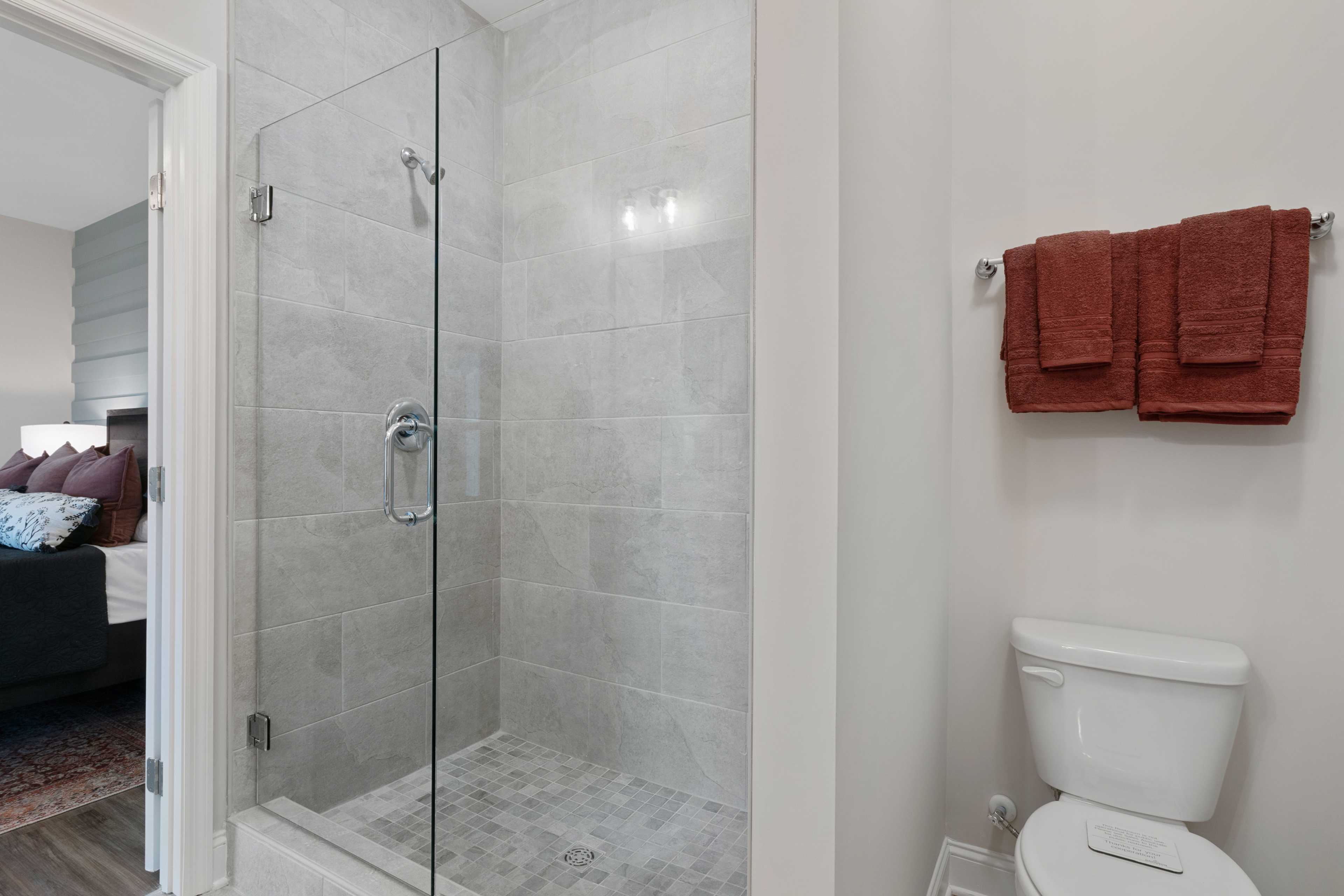 Modern bathroom at The Retreat at Cain Park in Hartselle Alabama with frameless glass shower, subway tiles and rust towels