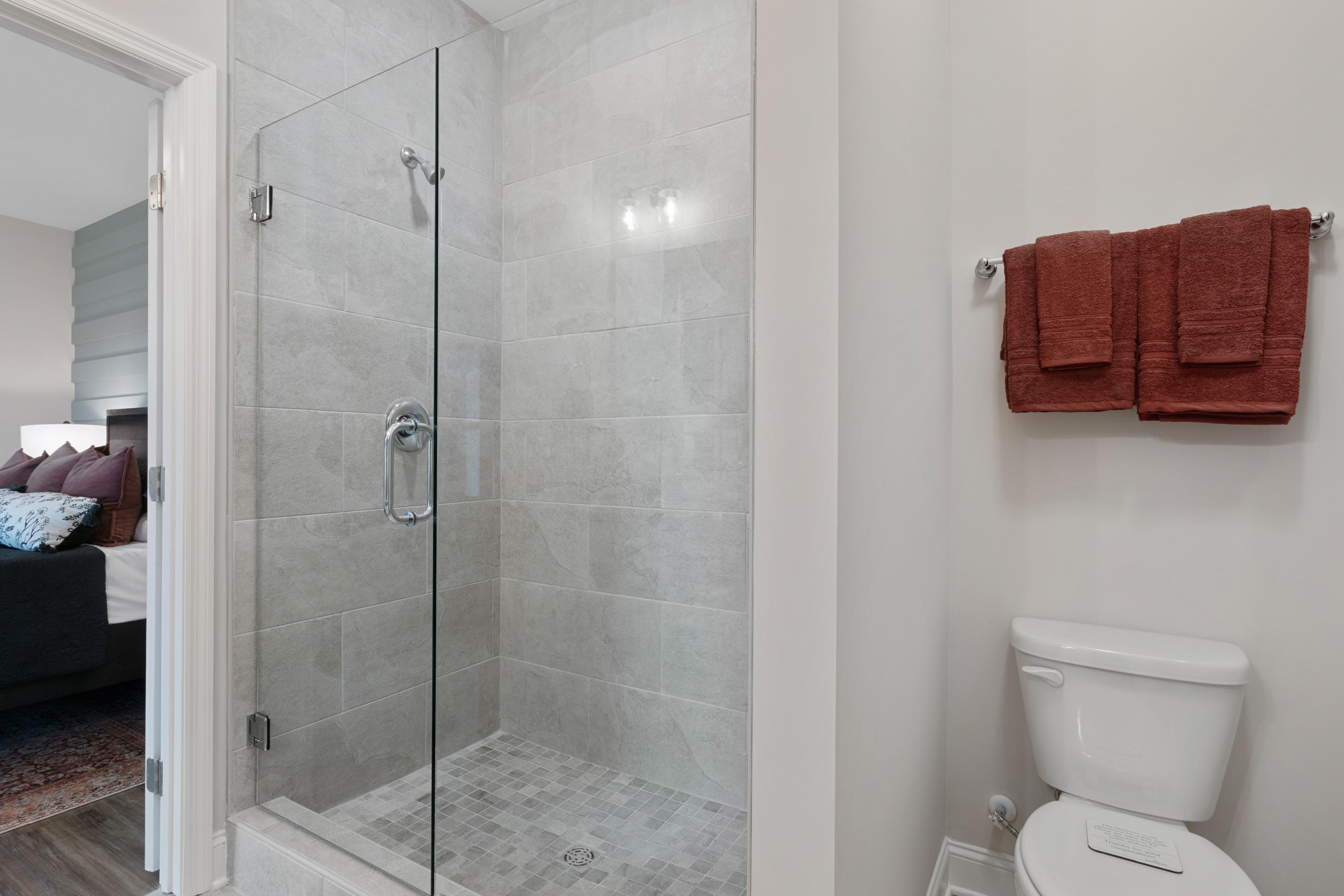 Modern bathroom at The Retreat at Cain Park in Hartselle Alabama with frameless glass shower, subway tiles and rust towels