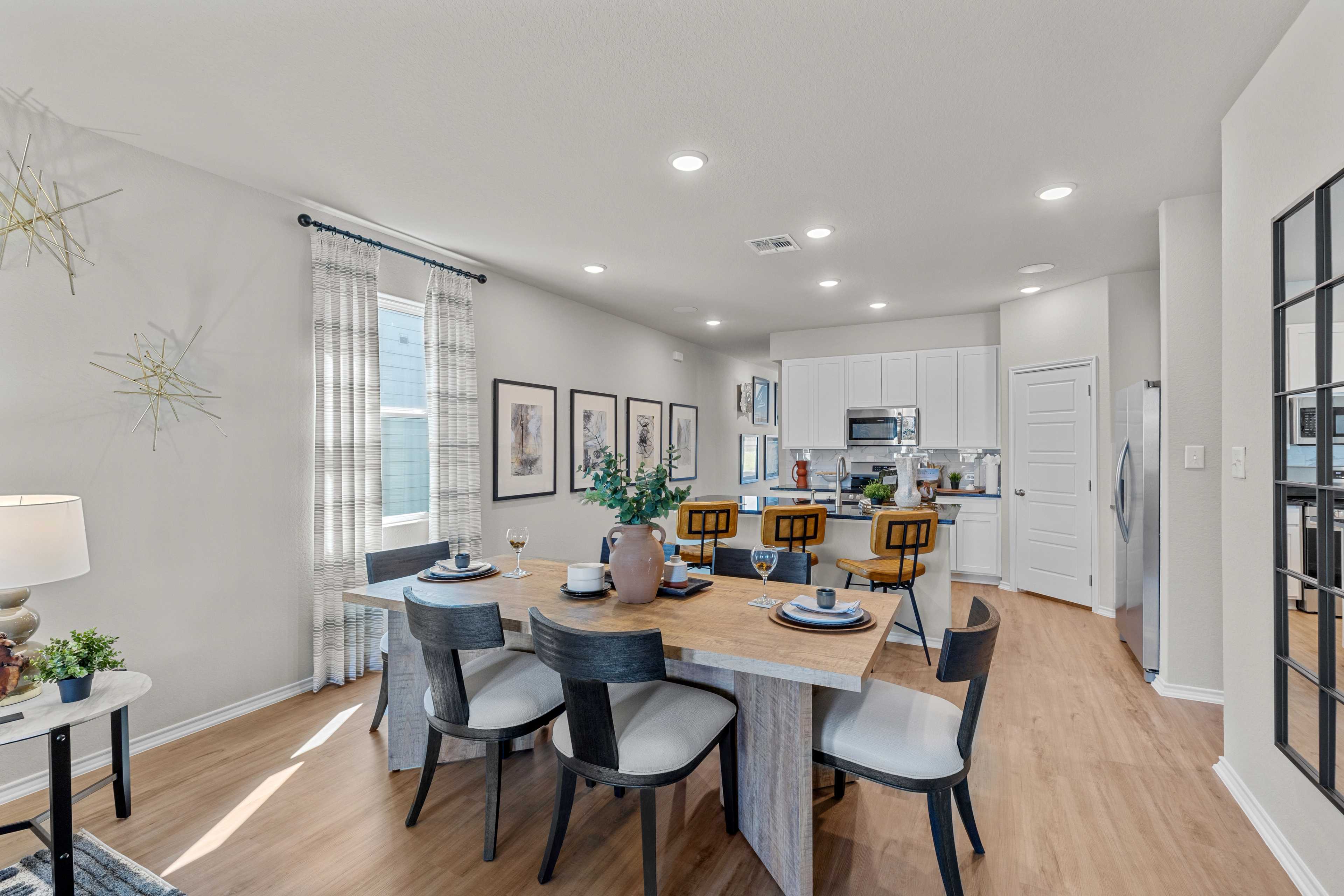 Spacious open-concept dining area with modern kitchen in Applewhite Meadows, San Antonio TX by Davidson Homes, hardwood floors and large windows