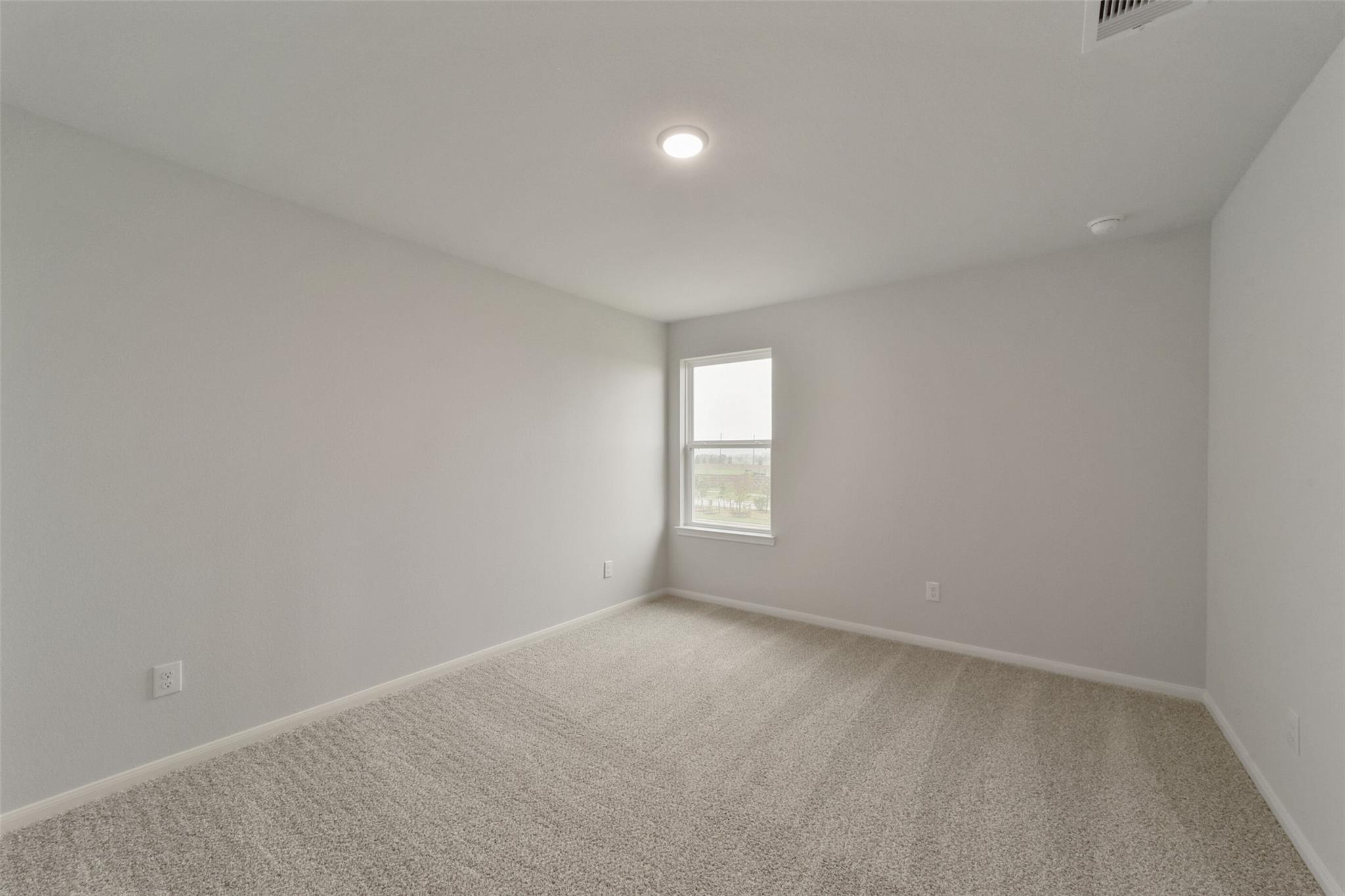 Empty bedroom featuring gray walls, beige carpet, large window with blinds in Davidson Homes The San Marcos E, Beasley, Texas