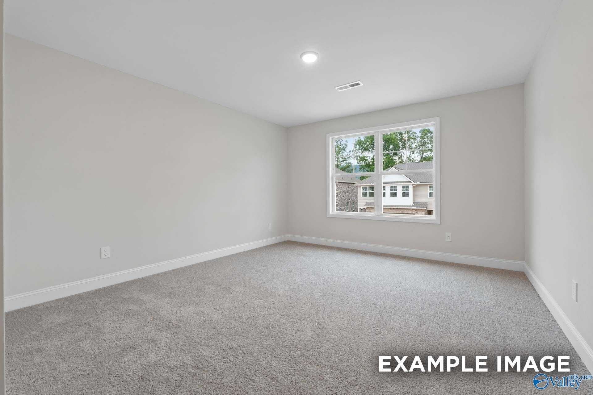 Bright secondary bedroom with large window overlooking trees and gray carpet in Davidson Homes The Camden D, Huntsville, Alabama