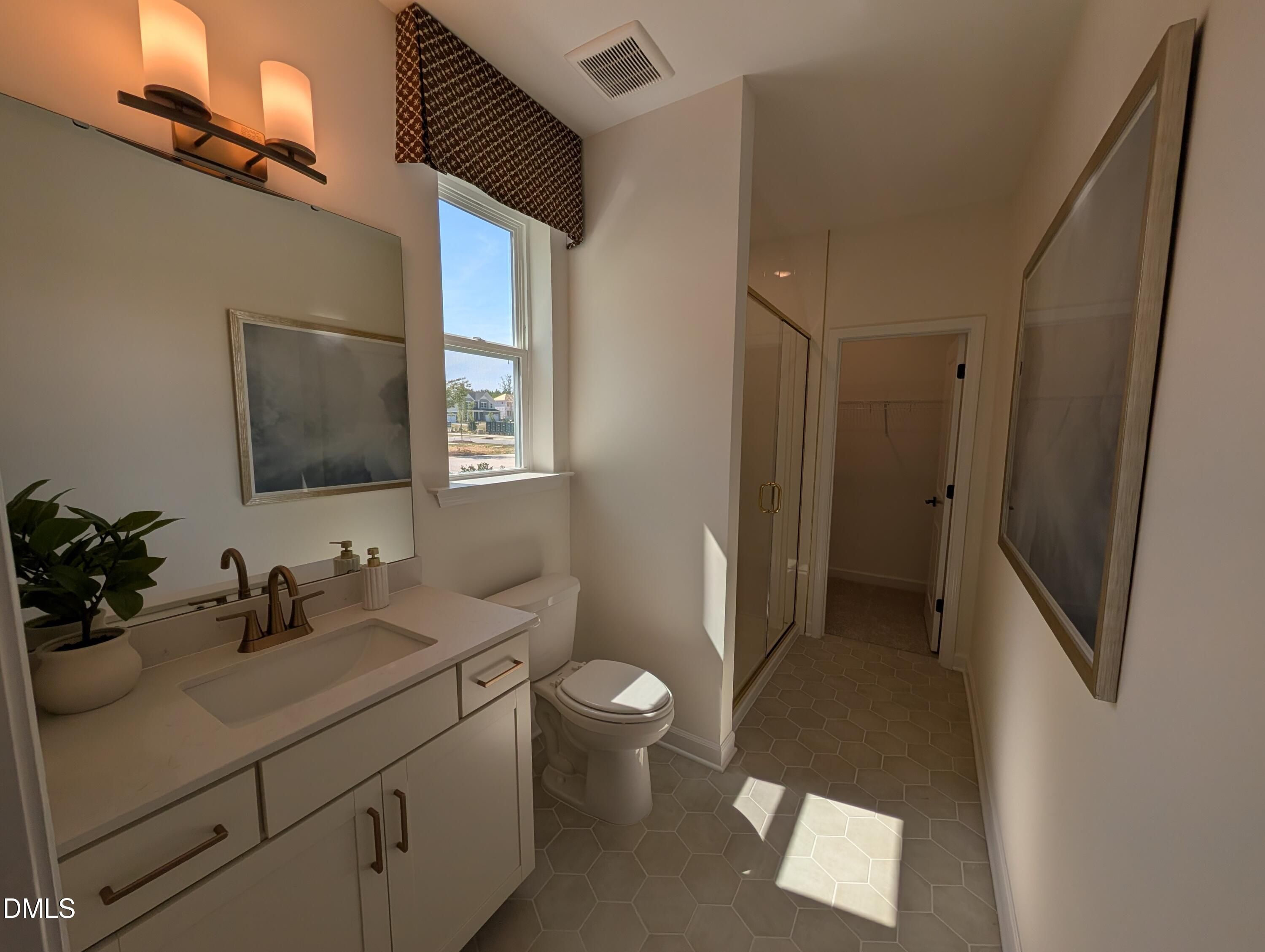 Modern bathroom with vanity, gold fixtures, and walk-in closet in The Aspen B floor plan at Wendell Ridge, Wendell, NC.