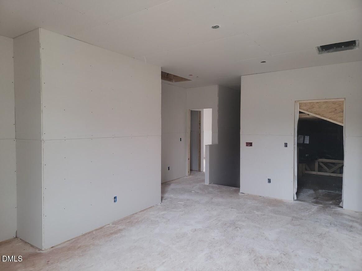 Unfinished spacious hallway with drywall walls, exposed ceiling joists, and rough-in electrical in The Ashport G home, Angier, NC