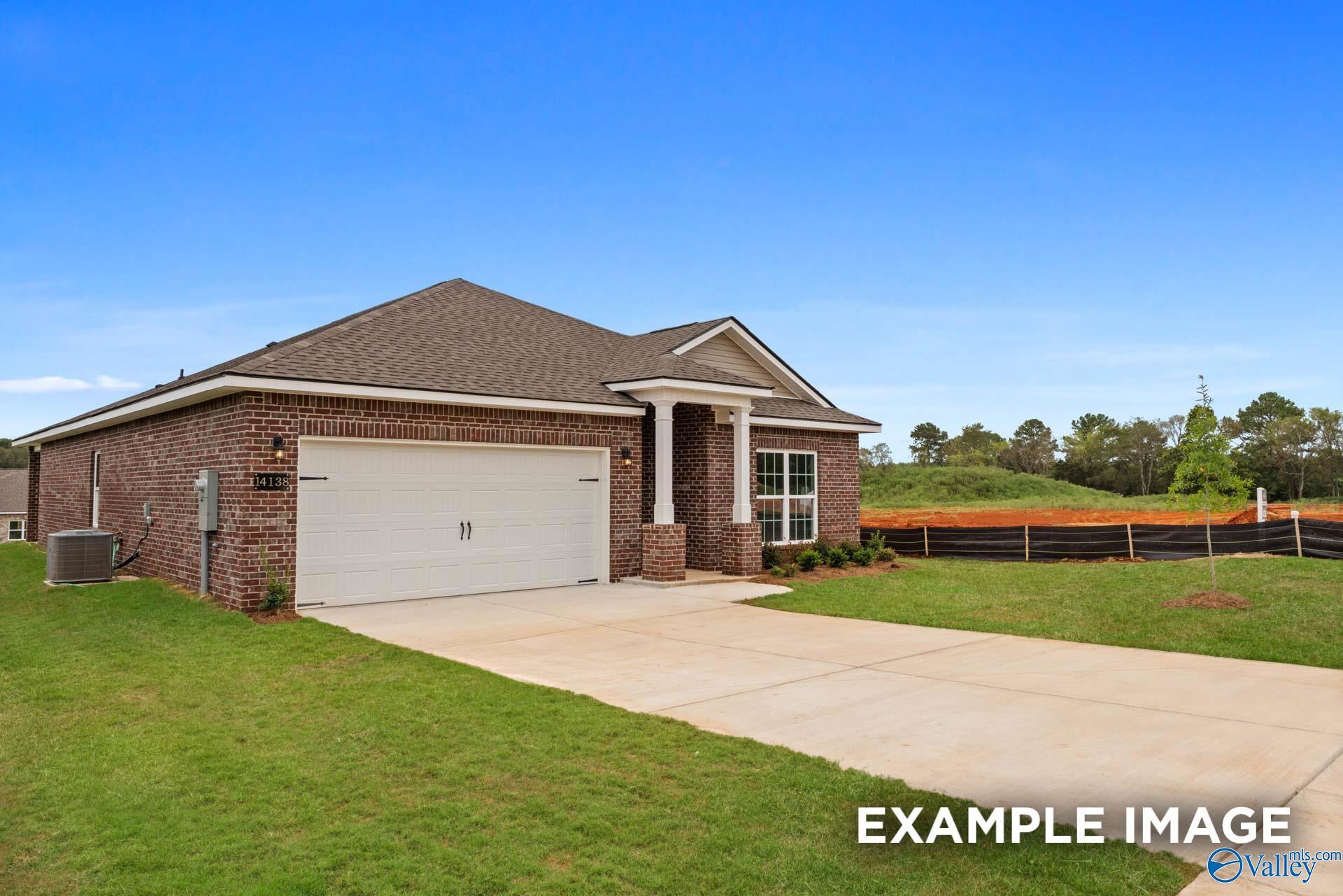 Brick single-story home with 2-car garage, front porch, and lush landscaping in Ivy Hills, Toney, Alabama