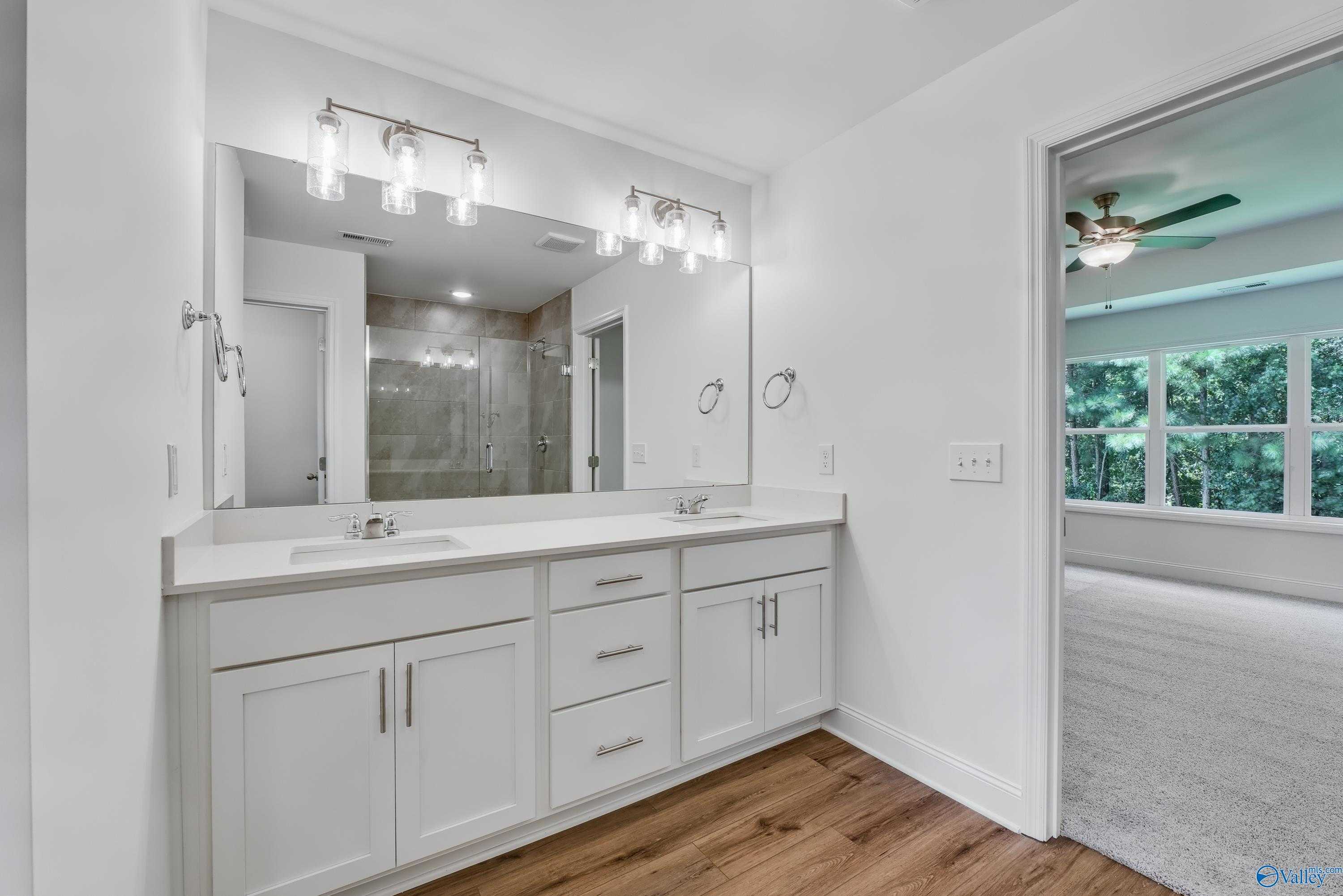Elegant master bathroom double vanity with white cabinets, quartz counters, and dual sinks in Davidson Homes The Shelby A, Arab, Alabama