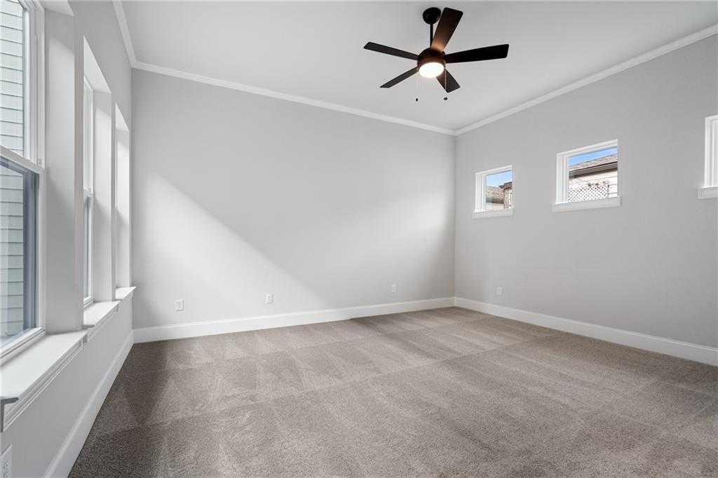 Spacious empty bedroom with gray walls, large windows, ceiling fan, and carpet in Davidson Homes Seaside B, Woodstock, GA