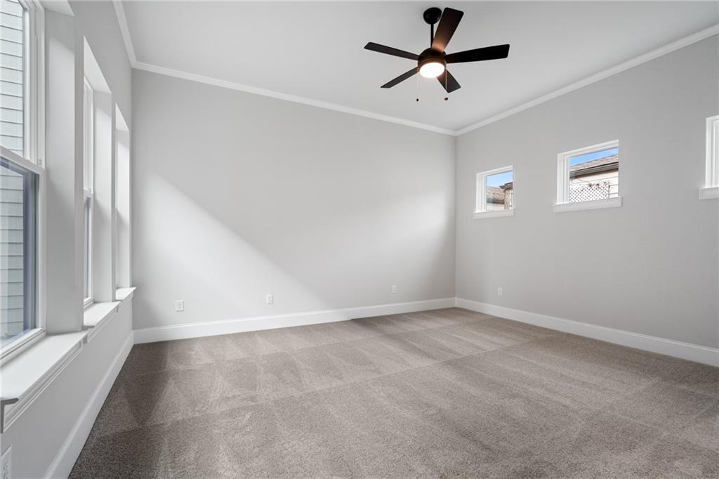 Spacious empty bedroom with gray walls, large windows, ceiling fan, and carpet in Davidson Homes Seaside B, Woodstock, GA