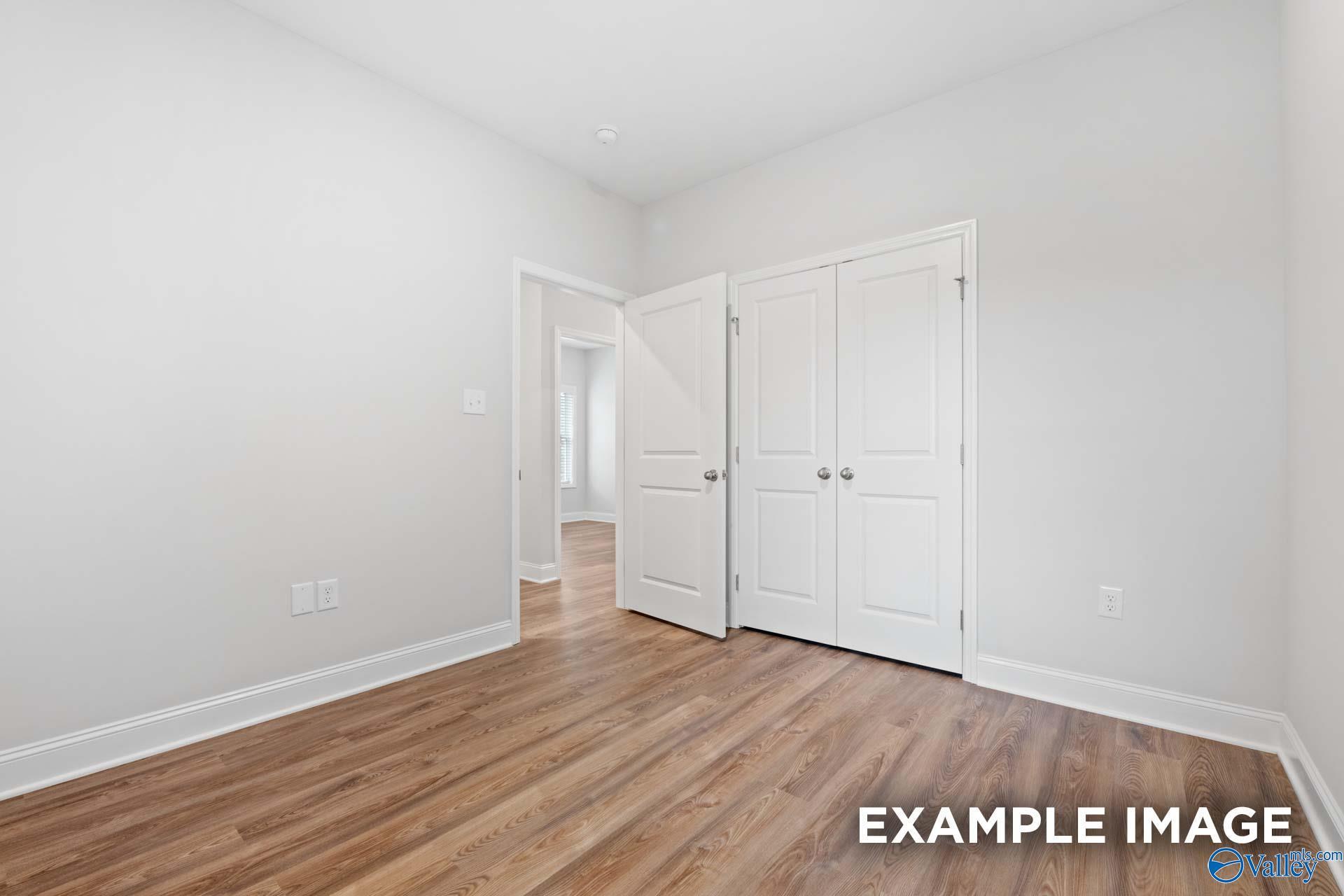 Spacious bedroom with open walk-in closet doors and luxury vinyl plank flooring in Davidson Homes The Cumberland, Decatur, Alabama