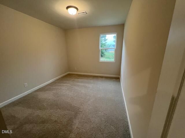 Spacious carpeted bedroom with neutral walls and window views in Davidson Homes The Willow D floor plan, Wellers Knoll, Lillington, NC
