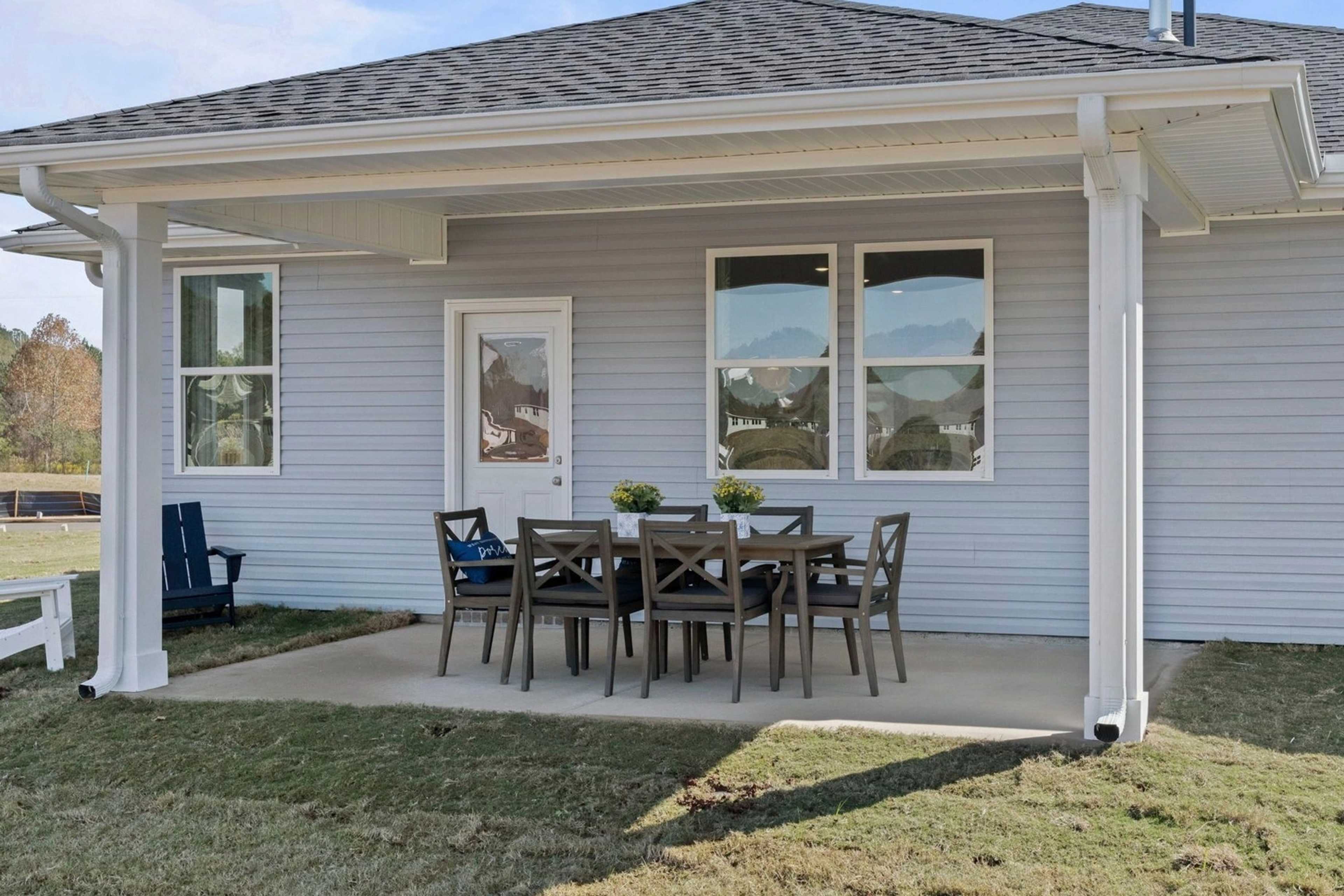 Covered back patio at Bailey Park in Fayetteville TN with gray siding, French doors, wooden dining set and Adirondack chairs