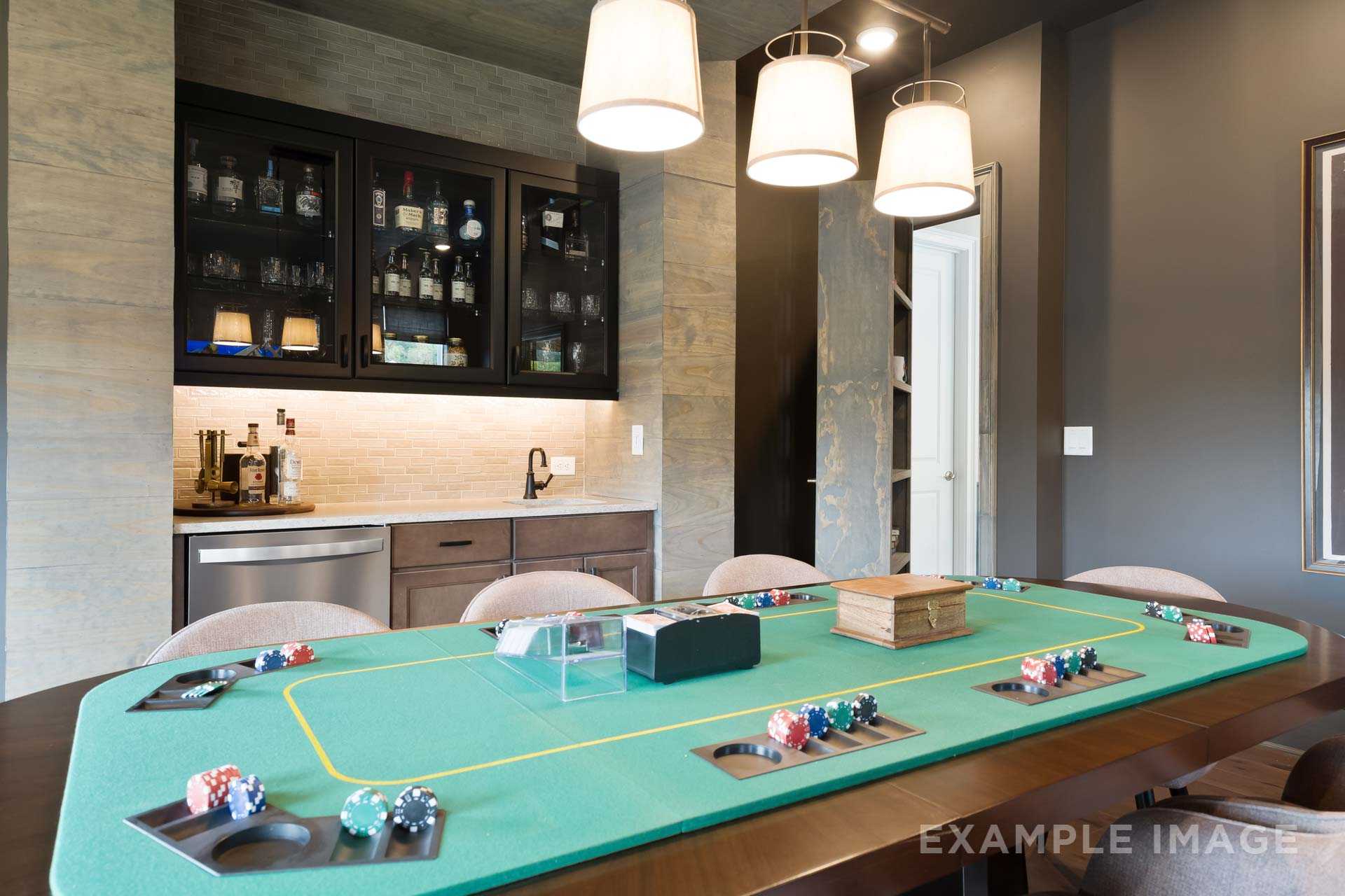 The Seaside game room featuring green felt poker table with chips, cards, and built-in bar with liquor display cabinets