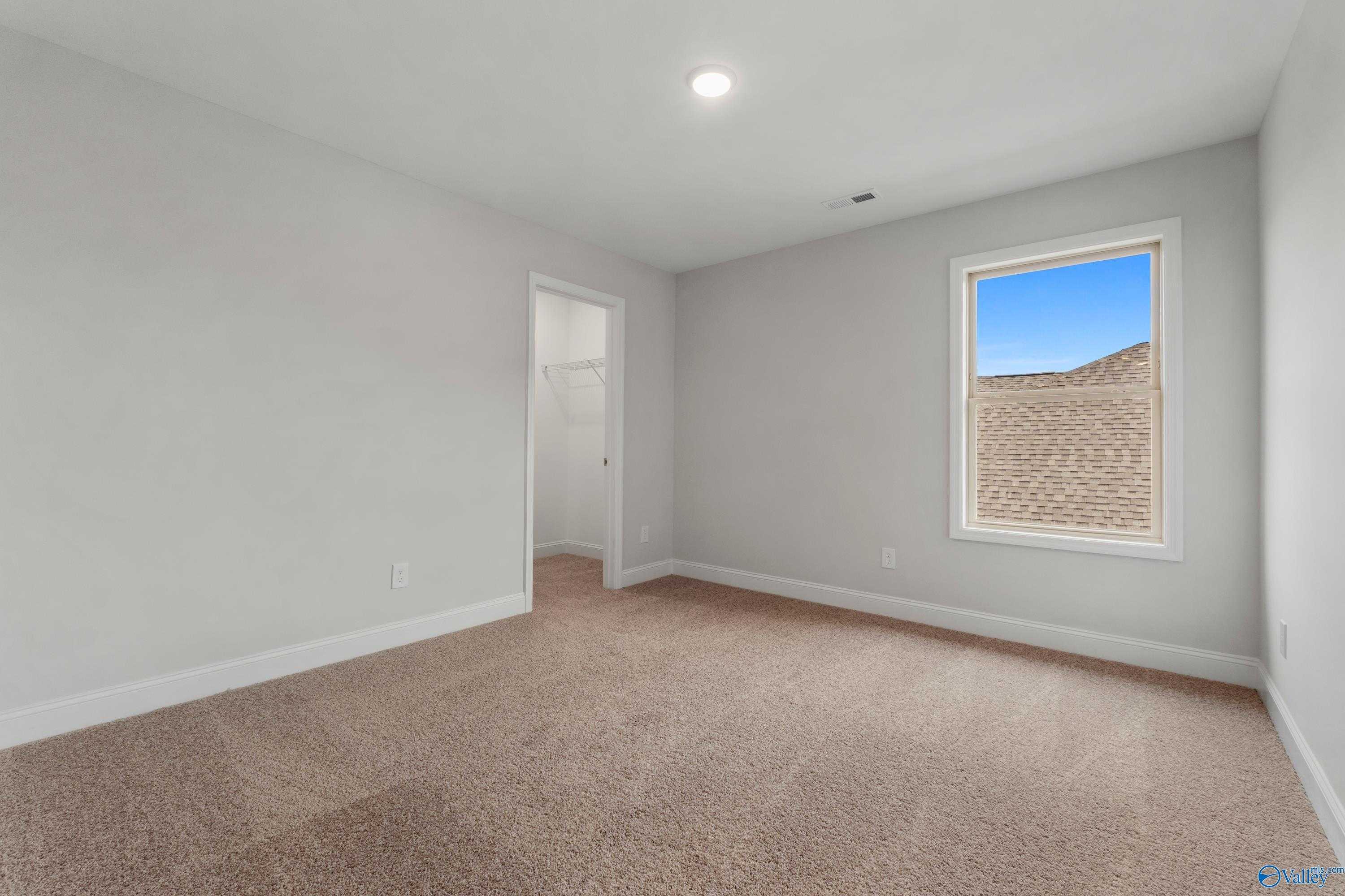 Bright secondary bedroom with large window, neutral walls, beige carpet in Davidson Homes Chelsea C, Harvest AL