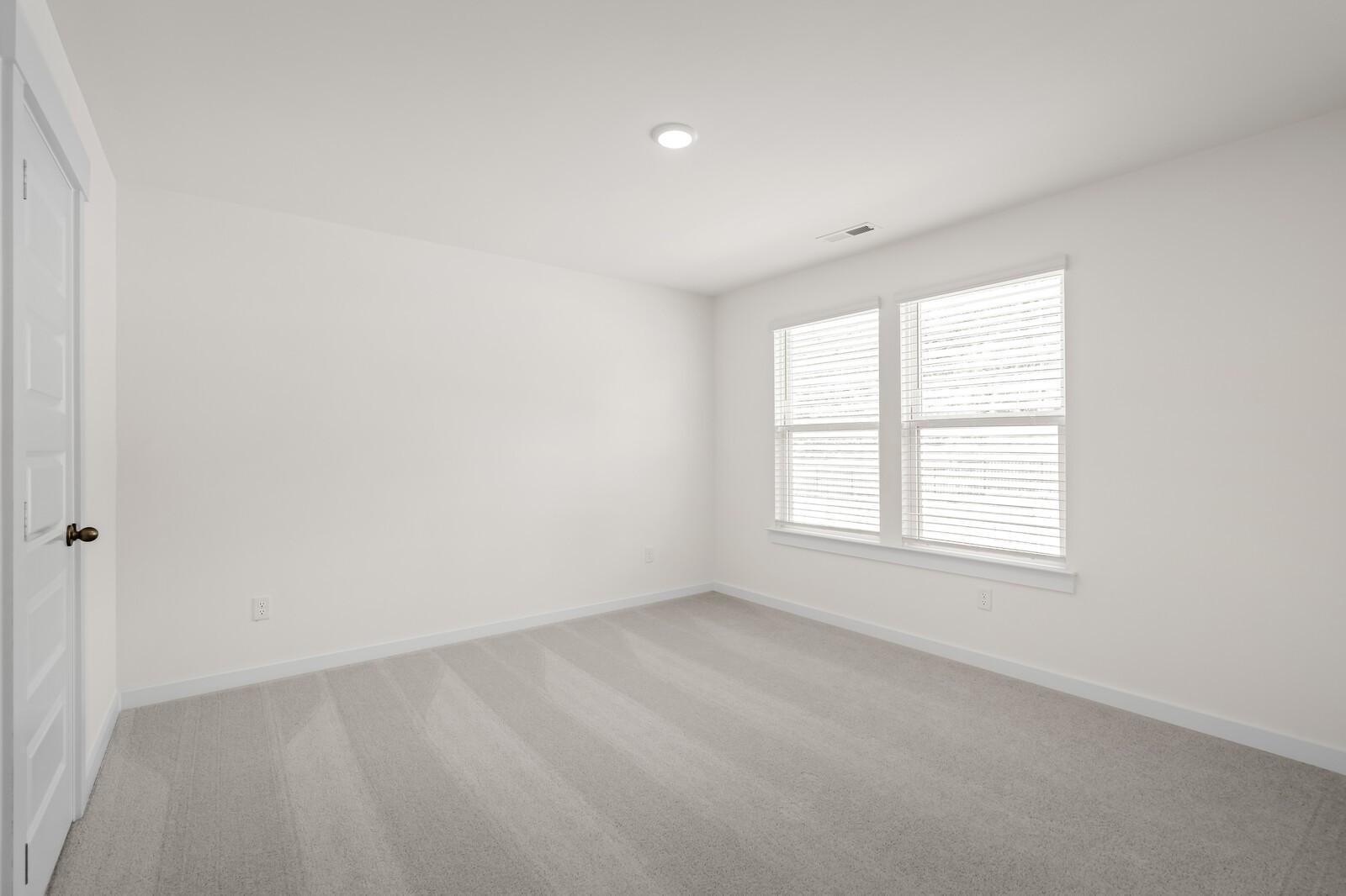 Bright, carpeted bedroom with white walls and natural light in The Willow floor plan at Woods Crossing, Gallatin, TN.
