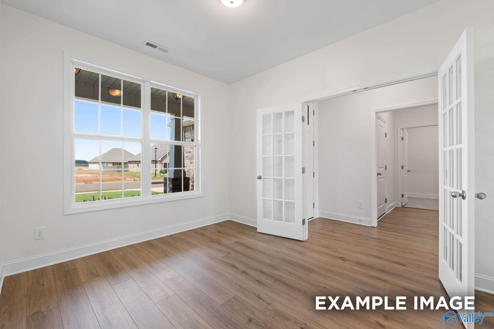 Bright study with hardwood floors, large windows to greenspace views, and open French doors in Davidson Homes The Rockford B, Athens, AL