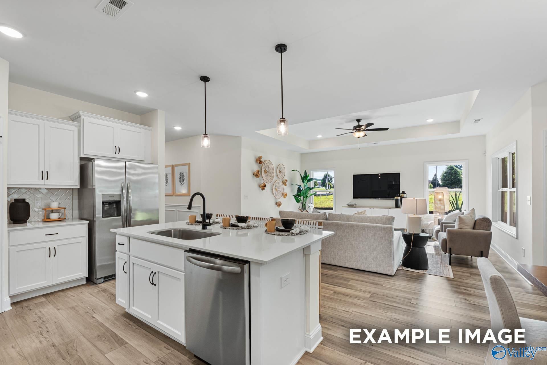 Open-concept kitchen with white cabinets, stainless appliances, and large island flowing into living room in Davidson Homes The Franklin, Huntsville, Alabama