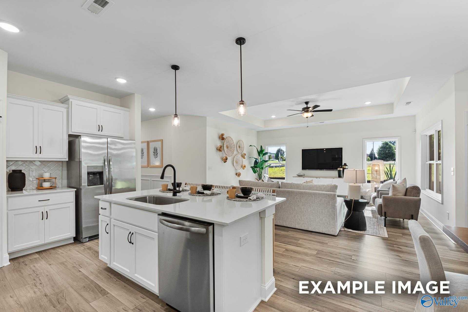 Bright open-concept kitchen with white cabinets, stainless appliances, and island in The Franklin 3-bedroom home, Huntsville AL