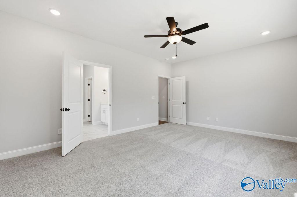 Spacious master bedroom with ceiling fan, gray carpet, and open en-suite bath in Davidson Homes Montgomery B, Hartselle AL