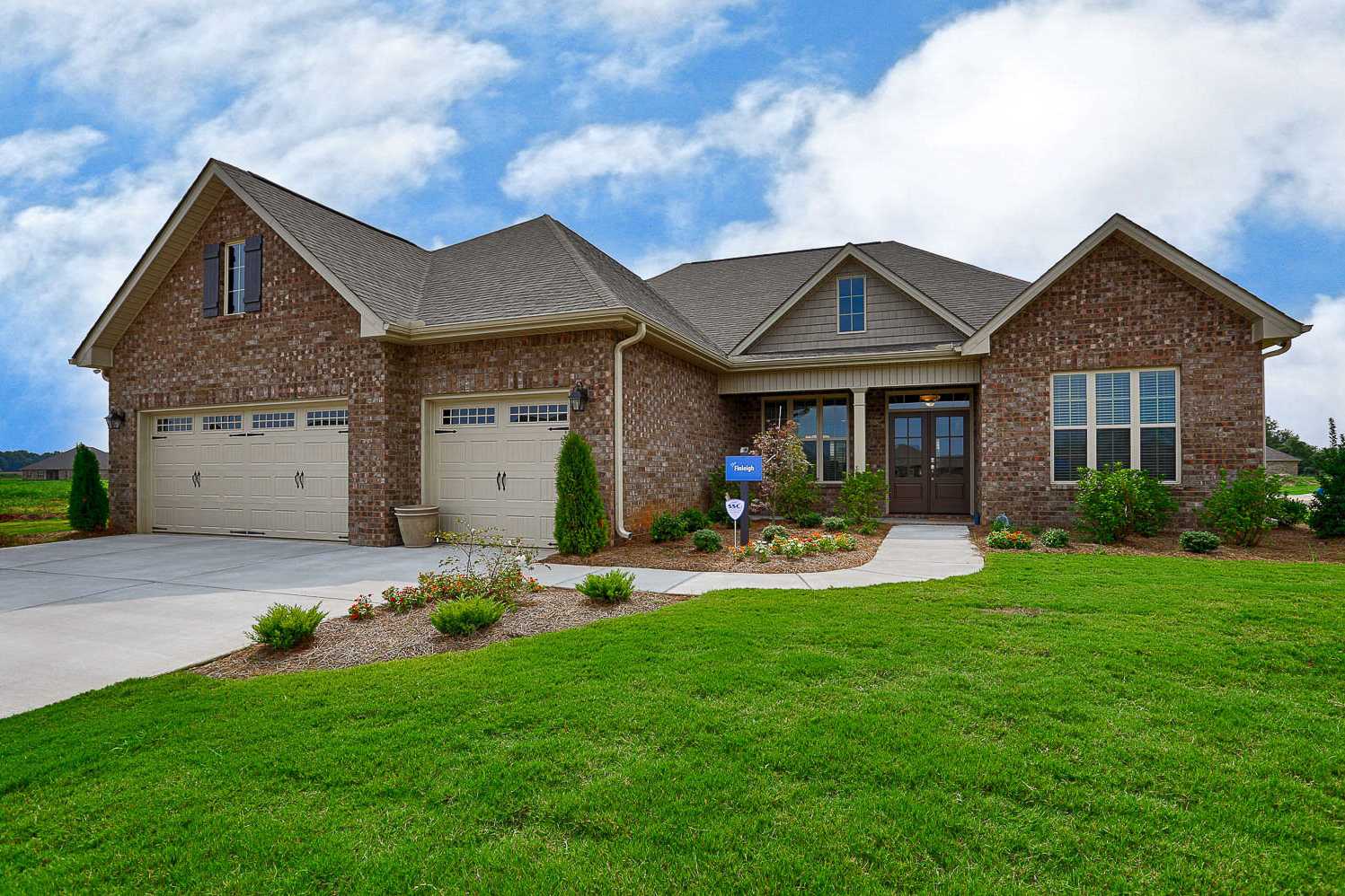 The Finleigh 2-story brick home design with 3-car garage, gabled roof, and lush lawn landscaping in Meridianville Alabama