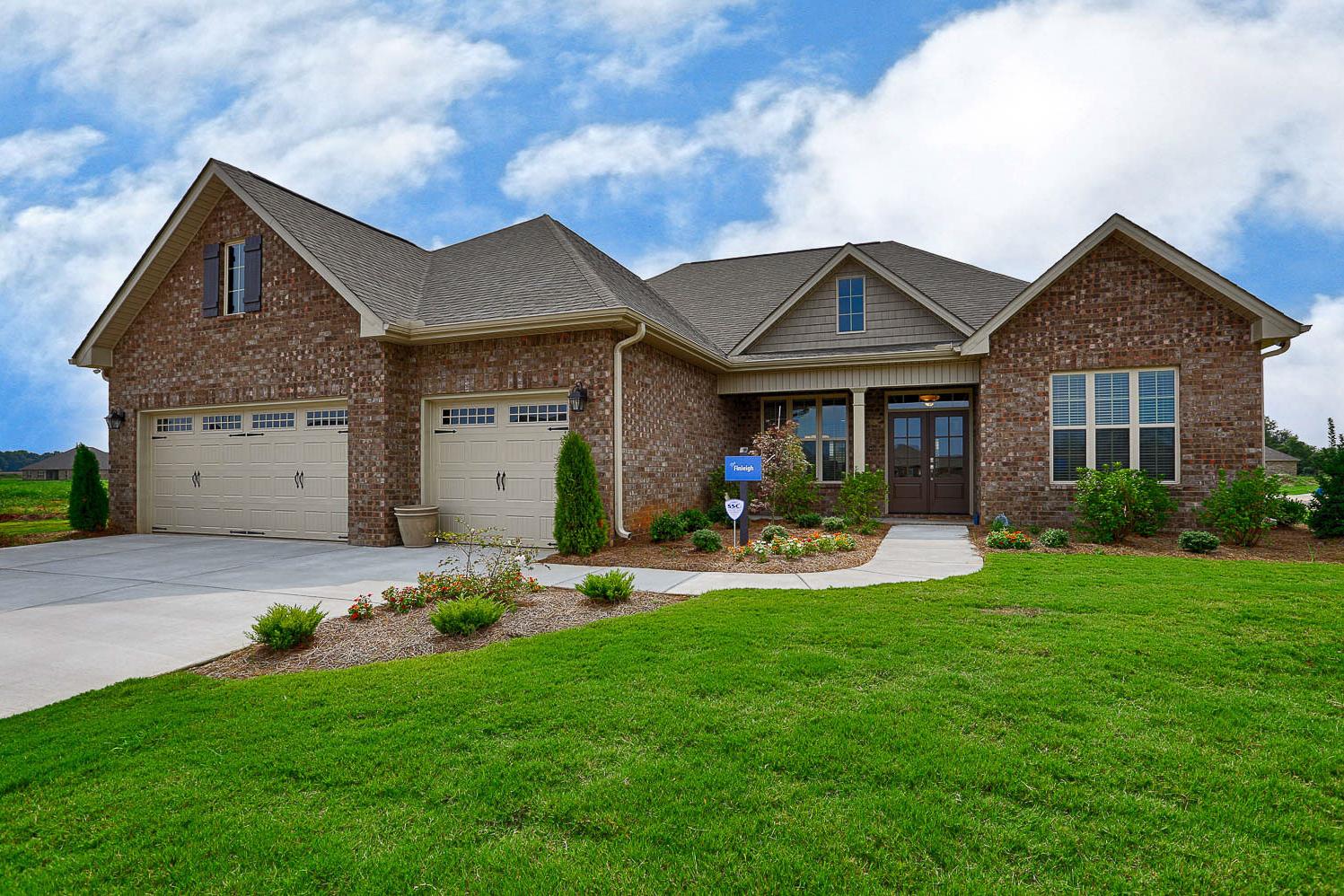 The Finleigh 2-story brick home design with 3-car garage, gabled roof, and lush lawn landscaping in Meridianville Alabama