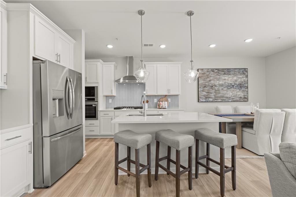 Modern kitchen with white cabinets, stainless appliances, and island seating in The Wake B floor plan, Hemingway, Cumming.