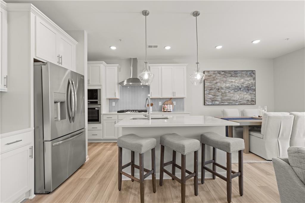 Modern kitchen with white cabinets, stainless appliances, and island seating in The Wake B floor plan, Hemingway, Cumming.