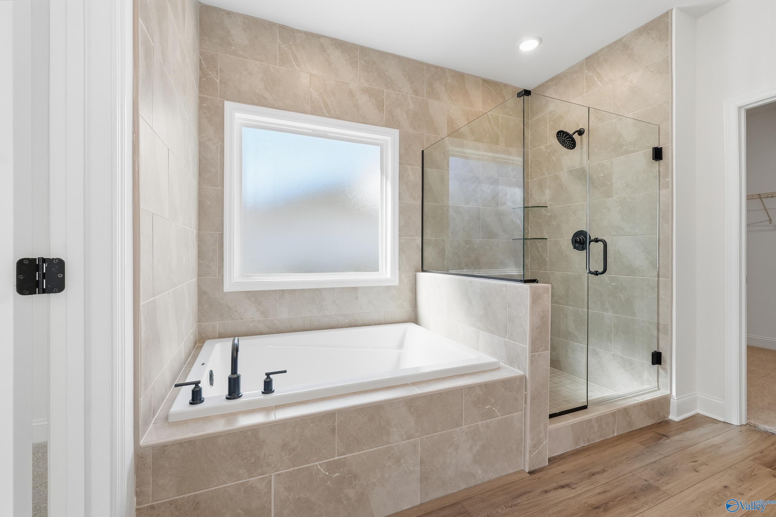 Elegant master bathroom with freestanding tub, glass shower, and frosted window in Davidson Homes The Rockford D, Hazel Green, Alabama