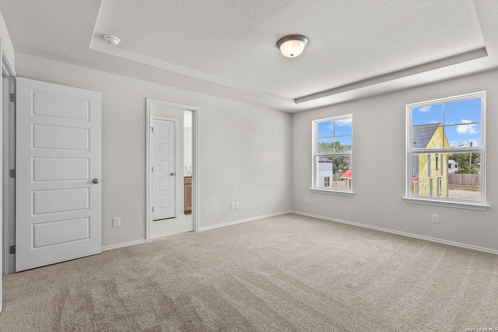 Bright primary bedroom with tray ceiling and en-suite bathroom in The Gillian B floor plan at Meadows at Oak Creek.