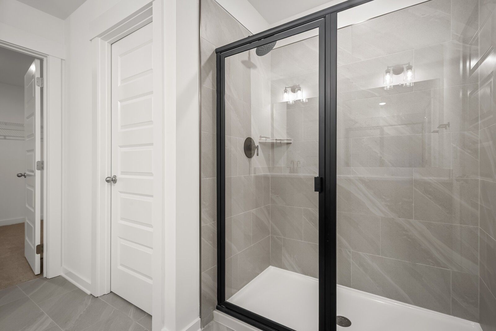 Modern master bathroom with black-framed glass shower and subway tile walls in Davidson Homes The Logan C, Gallatin, TN