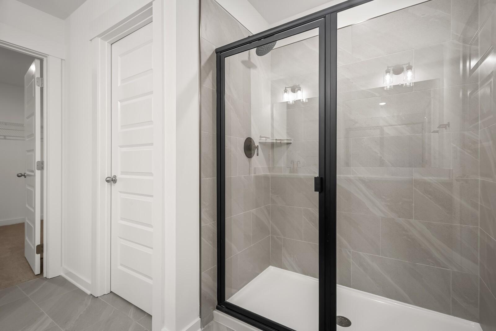 Modern master bathroom with black-framed glass shower and subway tile walls in Davidson Homes The Logan C, Gallatin, TN