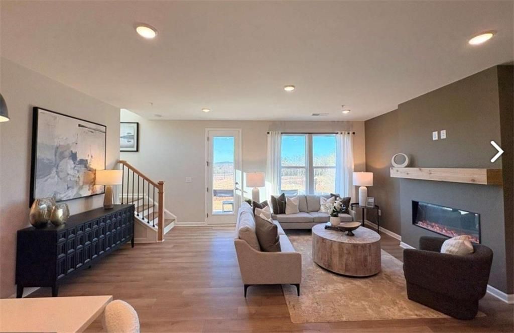Inviting living room with gas fireplace, beige sofa, wooden coffee table, and staircase in Davidson Homes The Durham D, Cumming, Georgia