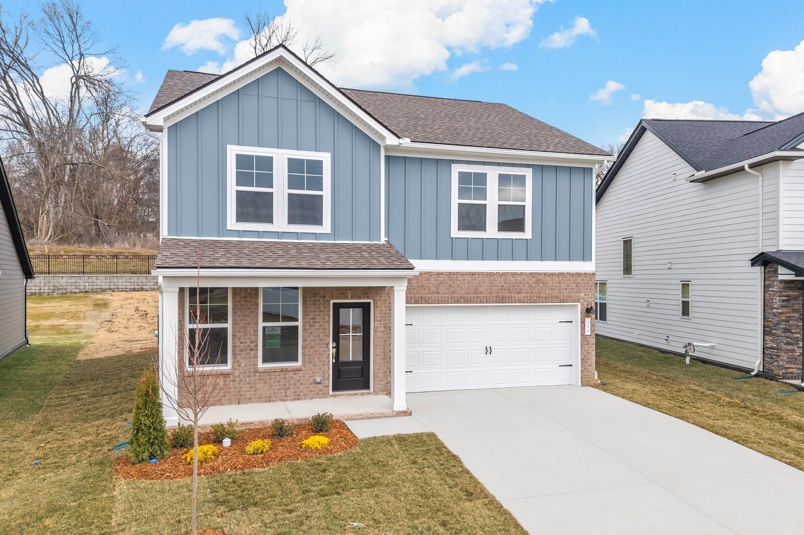 Modern two-story blue home with brick accents, 2-car garage, and landscaped front yard in Woods Crossing, Gallatin, Tennessee - Davidson Homes The Logan C
