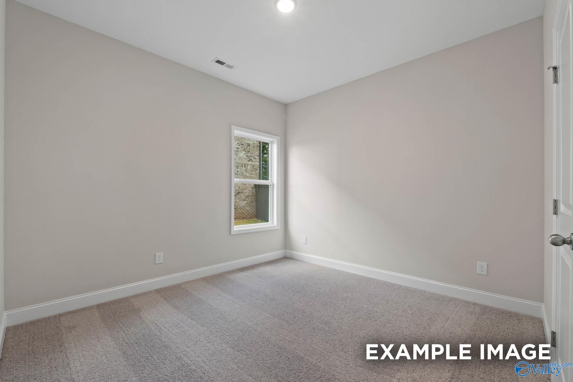 Bright secondary bedroom with light gray walls, carpet flooring, and window in Davidson Homes The Franklin V, Athens, Alabama