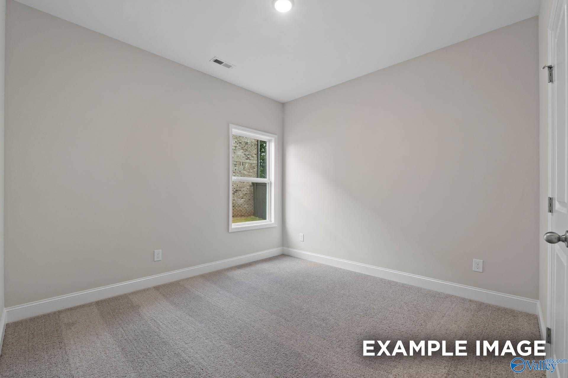 Bright secondary bedroom with light gray walls, carpet flooring, and window in Davidson Homes The Franklin V, Athens, Alabama