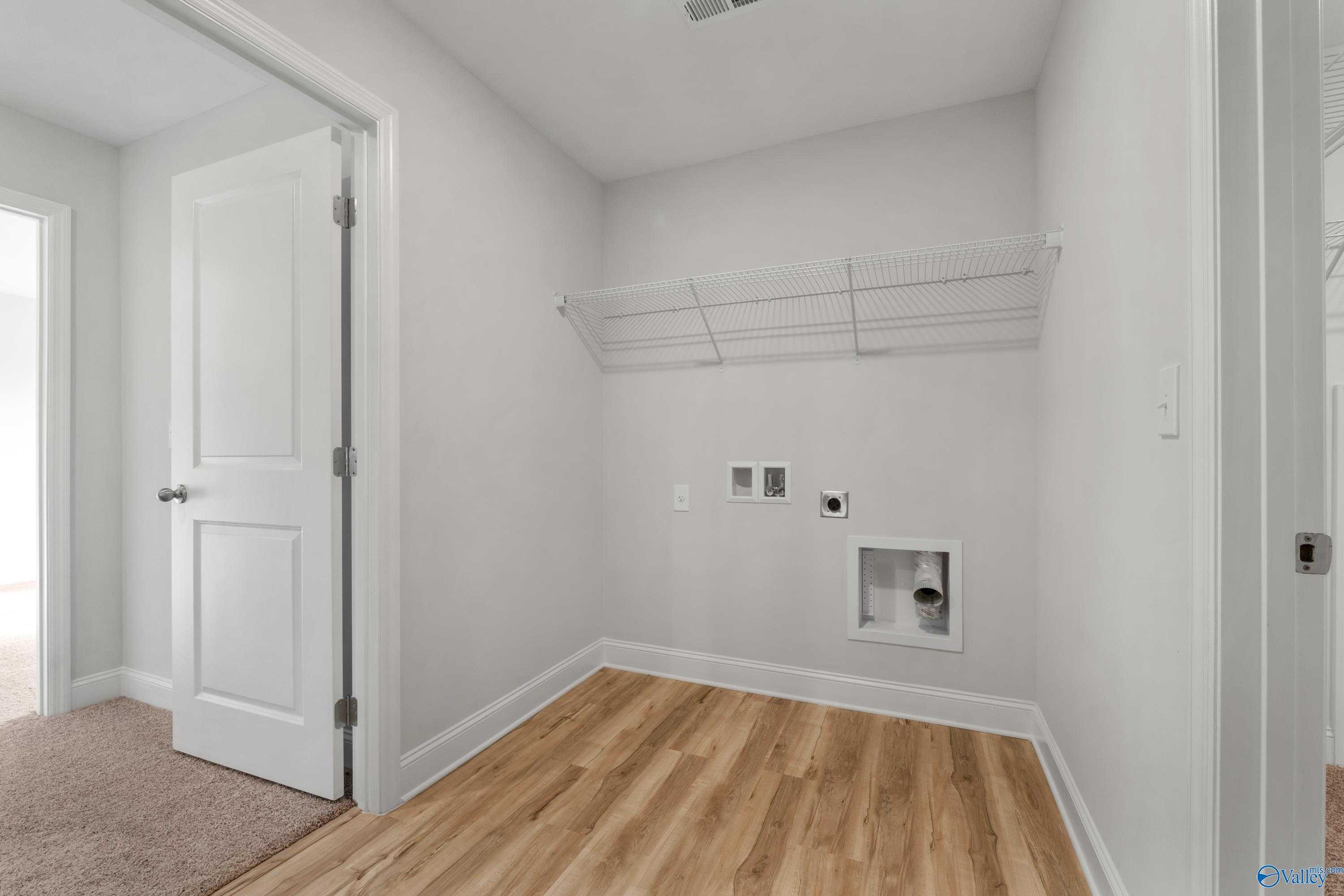 Bright laundry room with wooden hanging rod, washer/dryer hookups in Davidson Homes The Chelsea C, Creekside, Harvest, Alabama