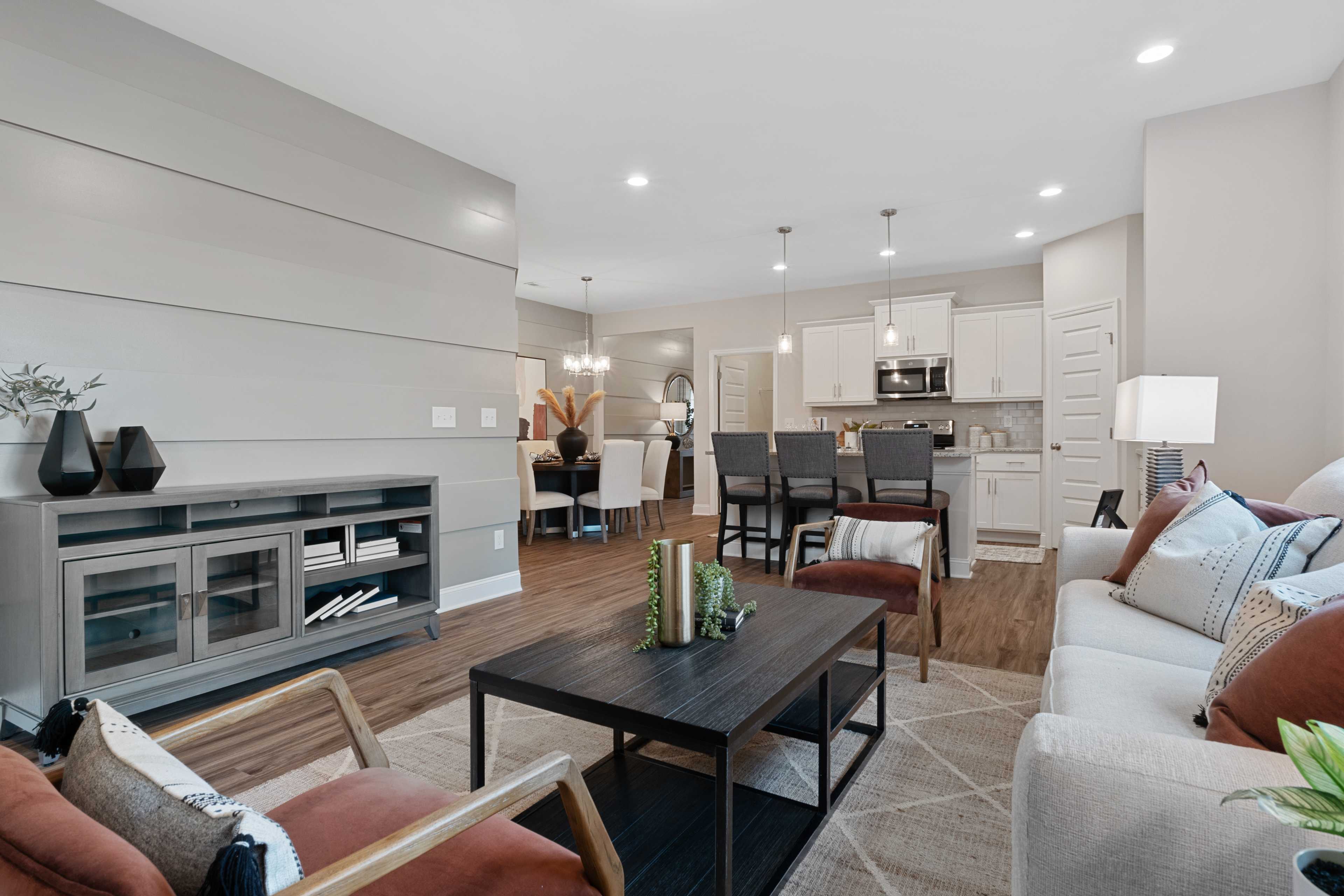 Spacious open-concept living room and kitchen at The Retreat at Cain Park in Hartselle AL with hardwood floors, gray accent wall, and modern seating