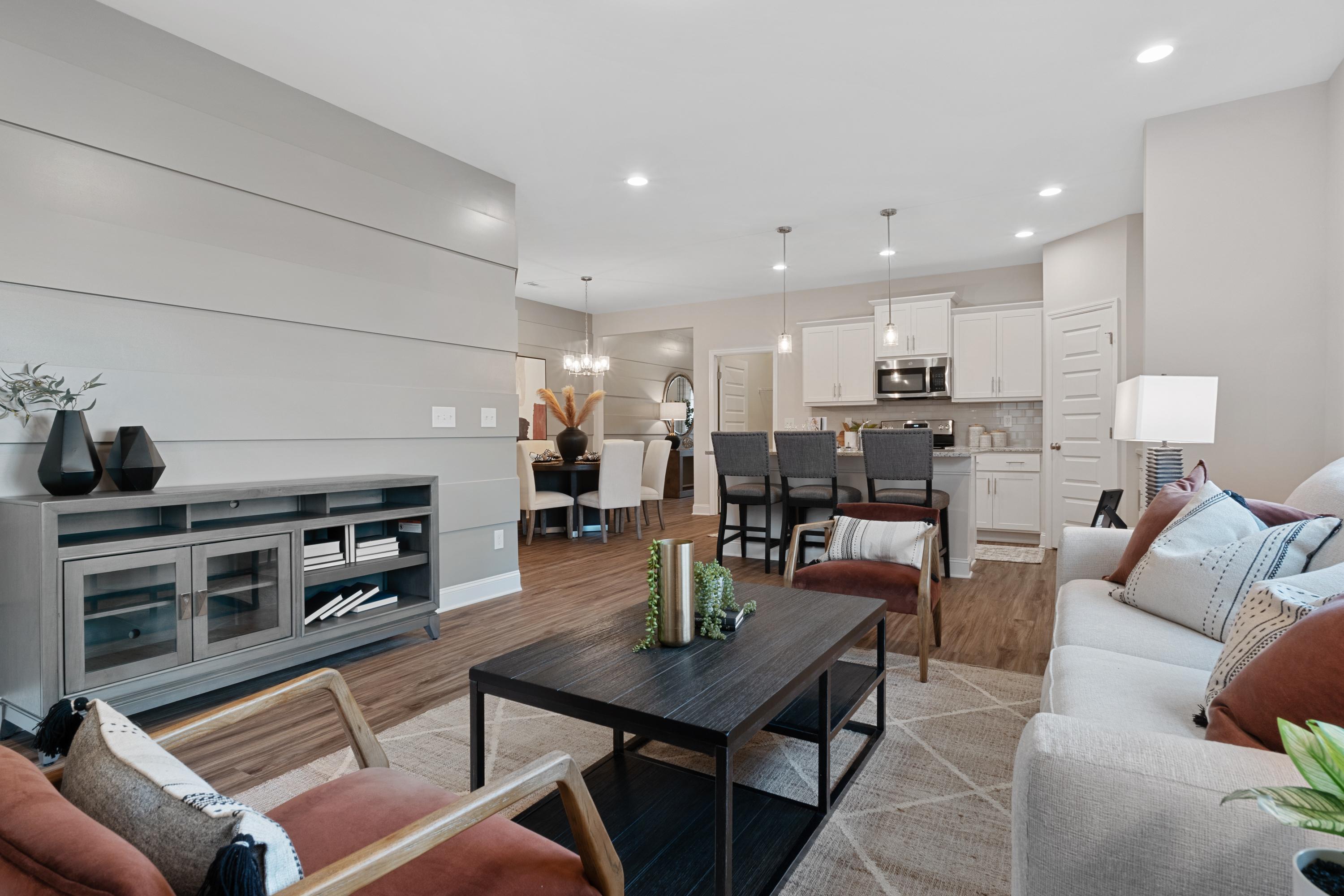 Spacious open-concept living room and kitchen at The Retreat at Cain Park in Hartselle AL with hardwood floors, gray accent wall, and modern seating