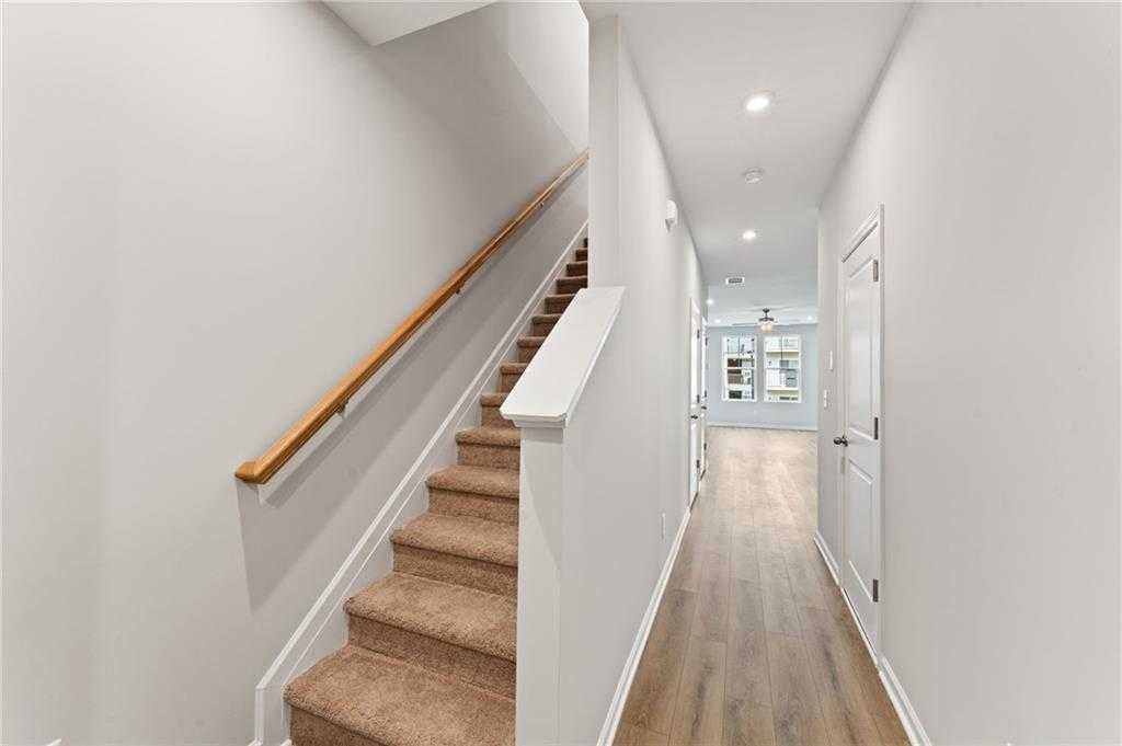 Spacious upstairs hallway with carpeted oak staircase and luxury vinyl plank flooring in The Monroe A by Davidson Homes, Emerson GA