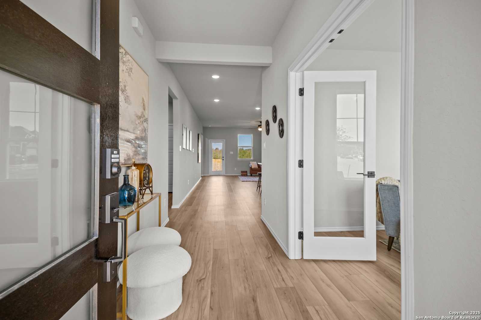 Elegant entryway with hardwood floors, console table, artwork, and open French doors in Davidson Homes The Douglas B, Converse, Texas