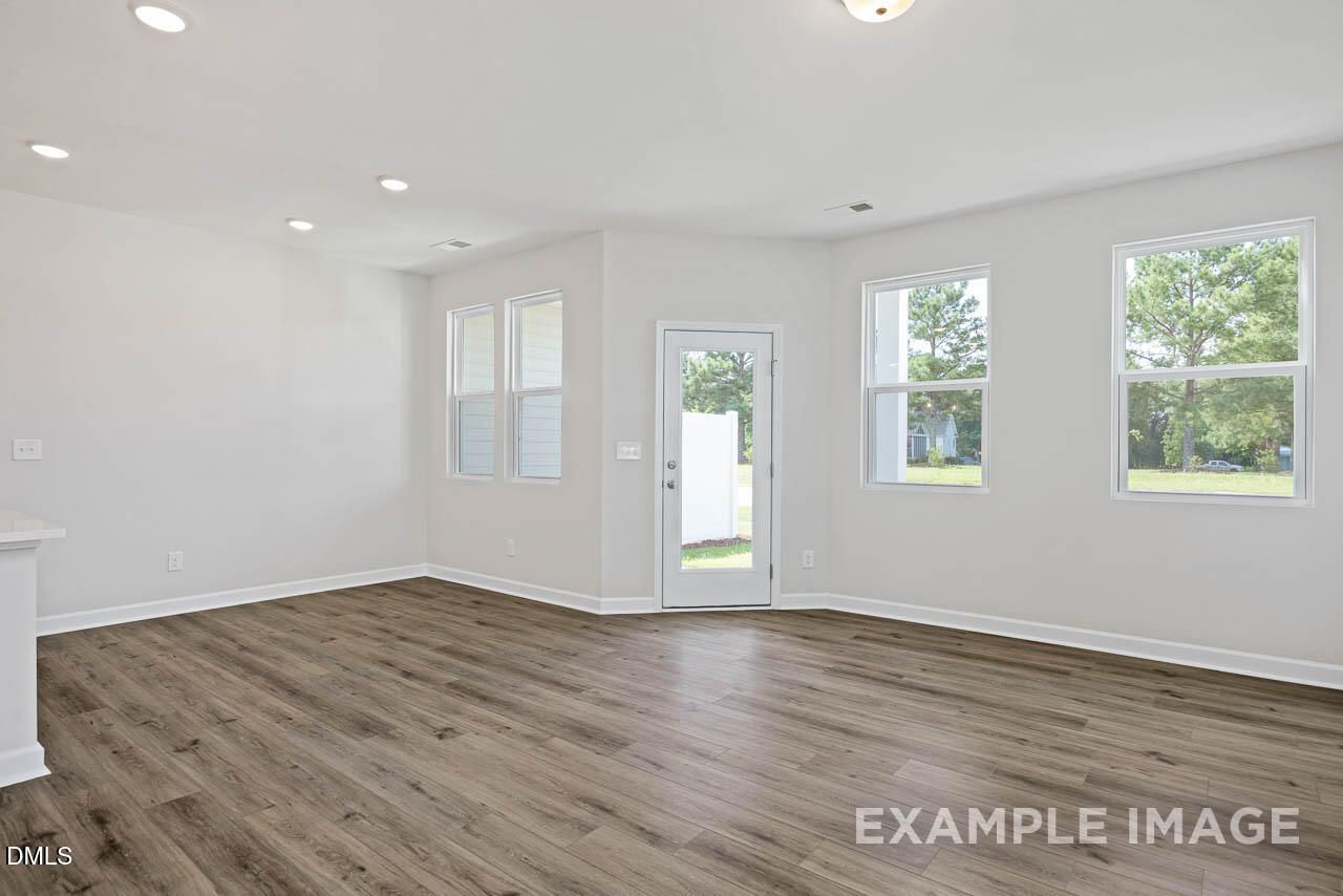 Bright, open-concept living area with wood-style flooring in The Graham floor plan at Springvale, Fuquay-Varina, NC.